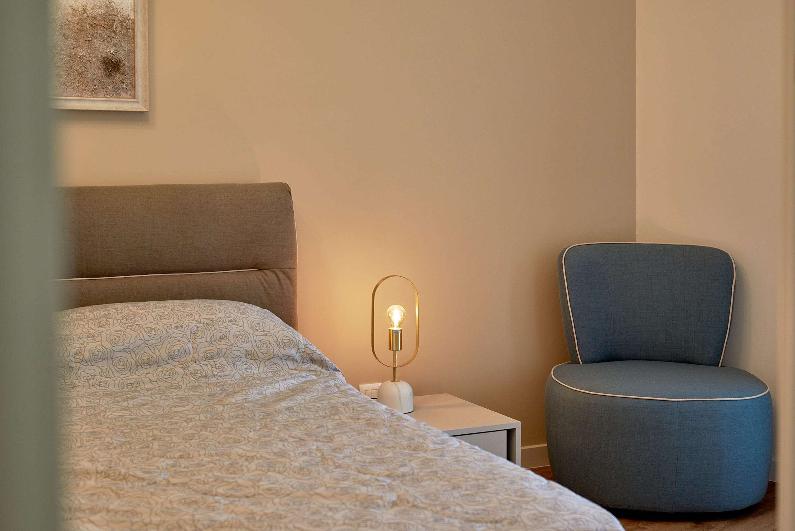 Cozy bedroom in an apartment, Bečići, Montenegro: double bed, blue armchair, and designer lamp.