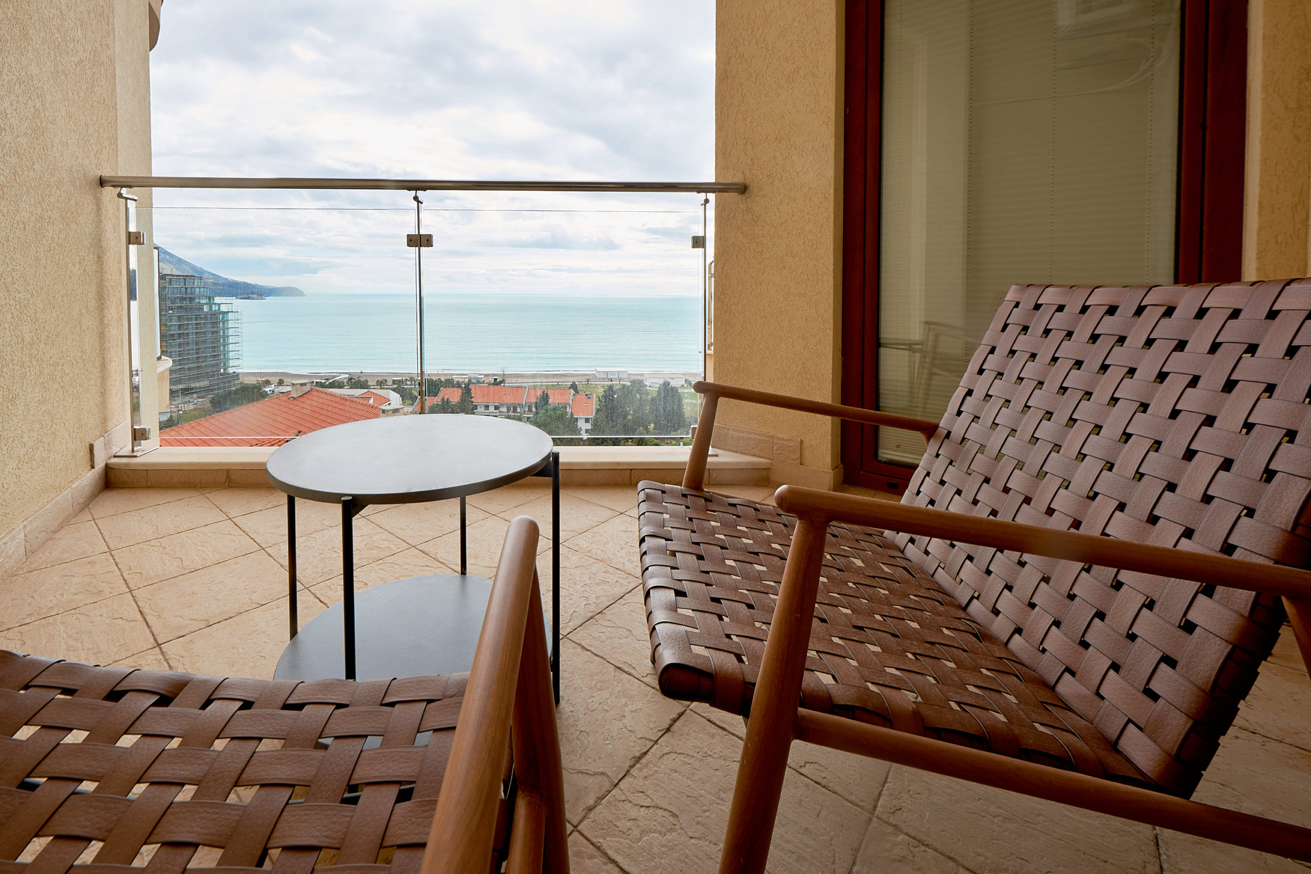 Balcony with wicker chairs and sea view in apartments, Bečići, Montenegro. Modern terrace with panoramic view.