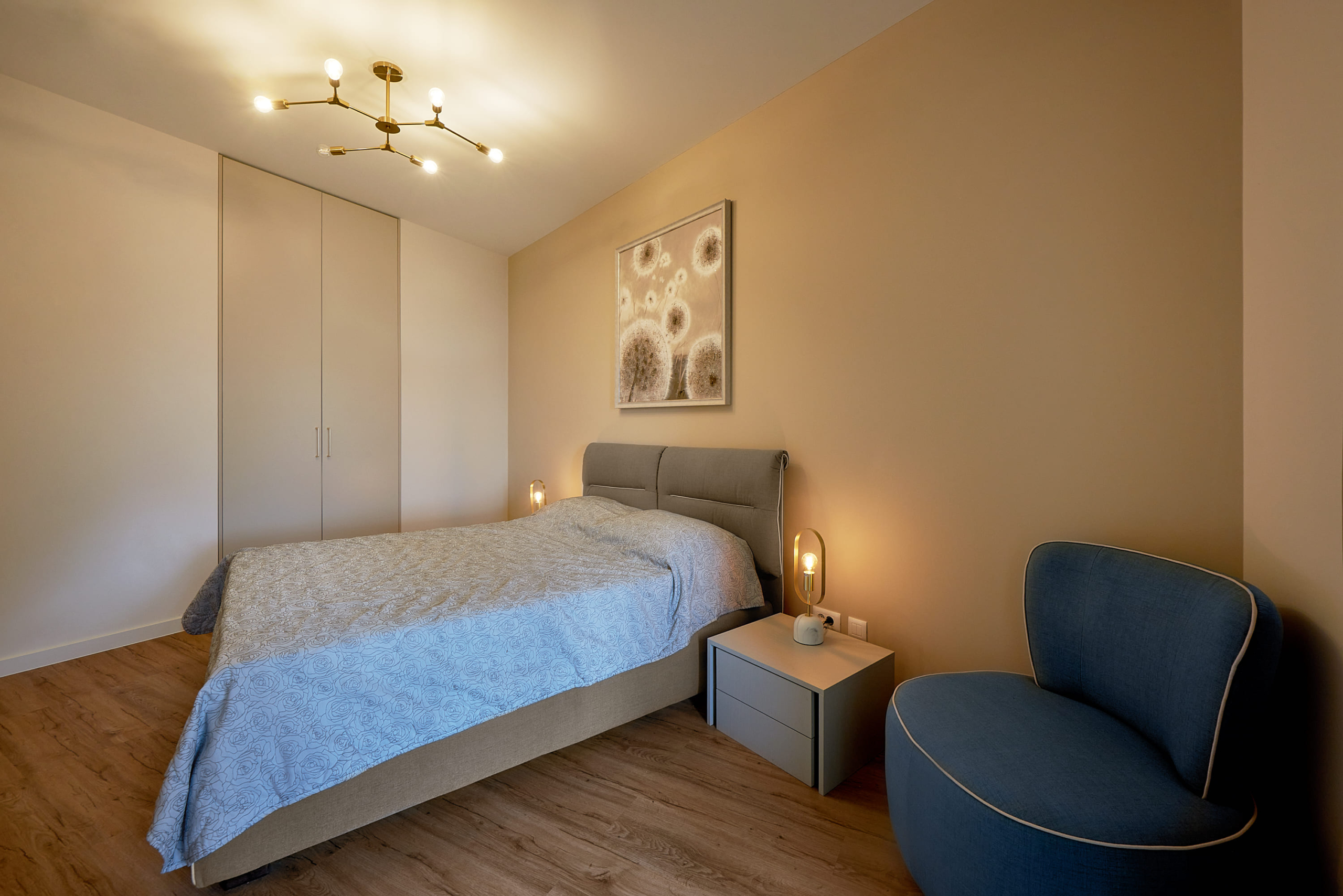Modern bedroom in an apartment in Bečići, Montenegro: double bed, built-in wardrobe, and blue armchair.