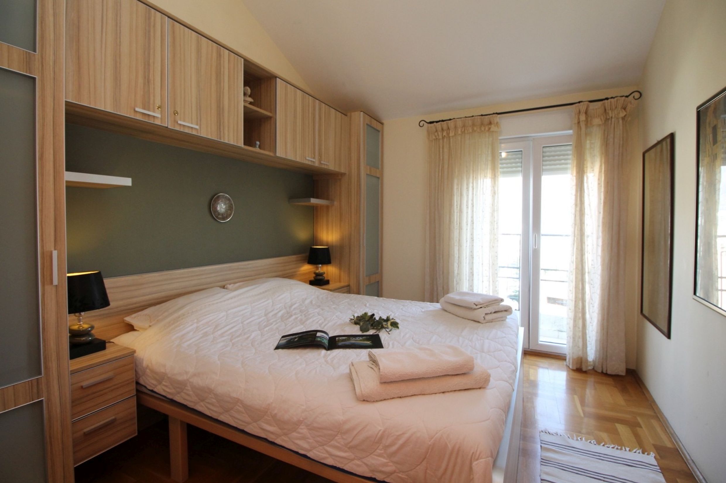 Cozy bedroom with a double bed and light wood furniture in an apartment, Bečići, Montenegro.