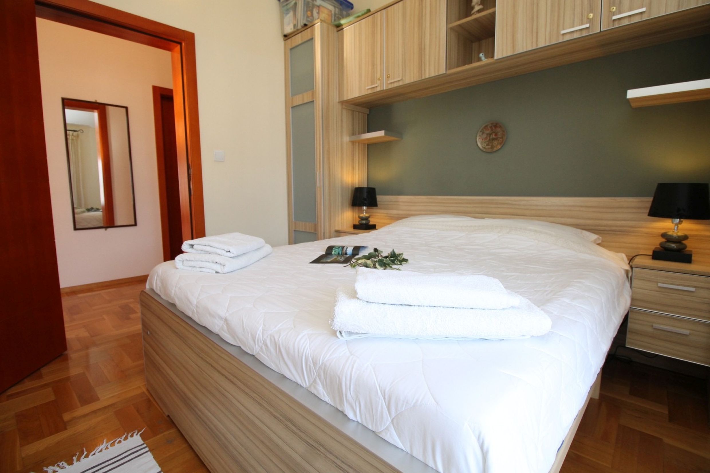 Cozy bedroom with a double bed in an apartment, Bečići, Montenegro: light furniture, parquet flooring, and stylish decor.