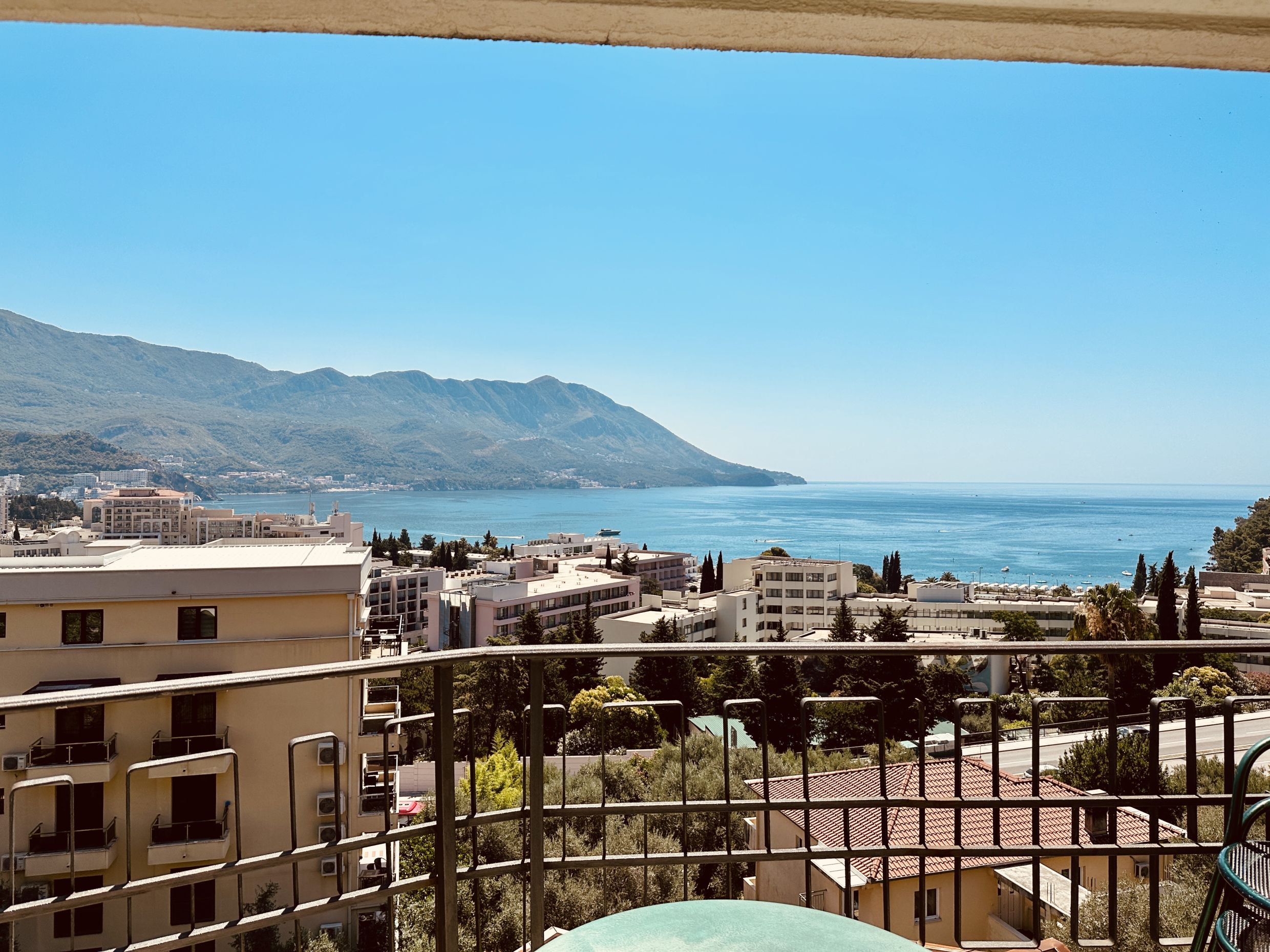 Panoramic view of the sea and mountains from the balcony of an apartment in Bečići, Montenegro, on a sunny summer day.