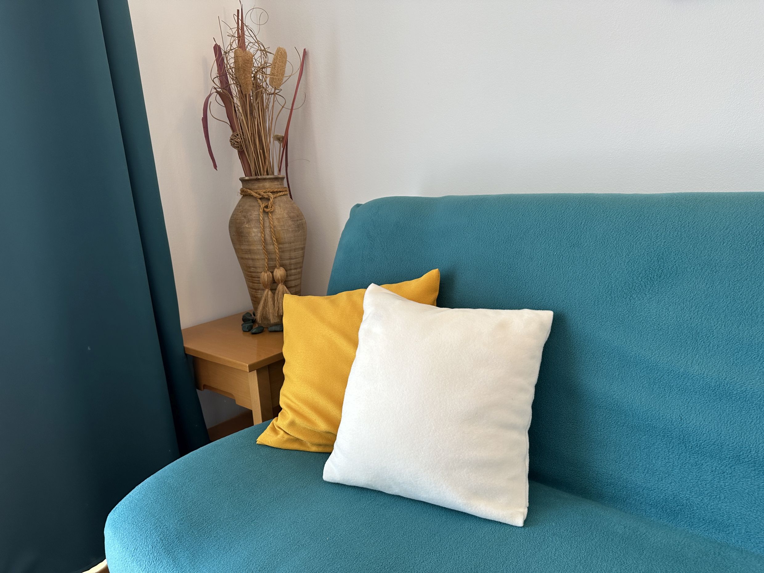 Turquoise sofa with decorative pillows in the interior of an apartment in Bečići, Montenegro. Cozy living room with decor.