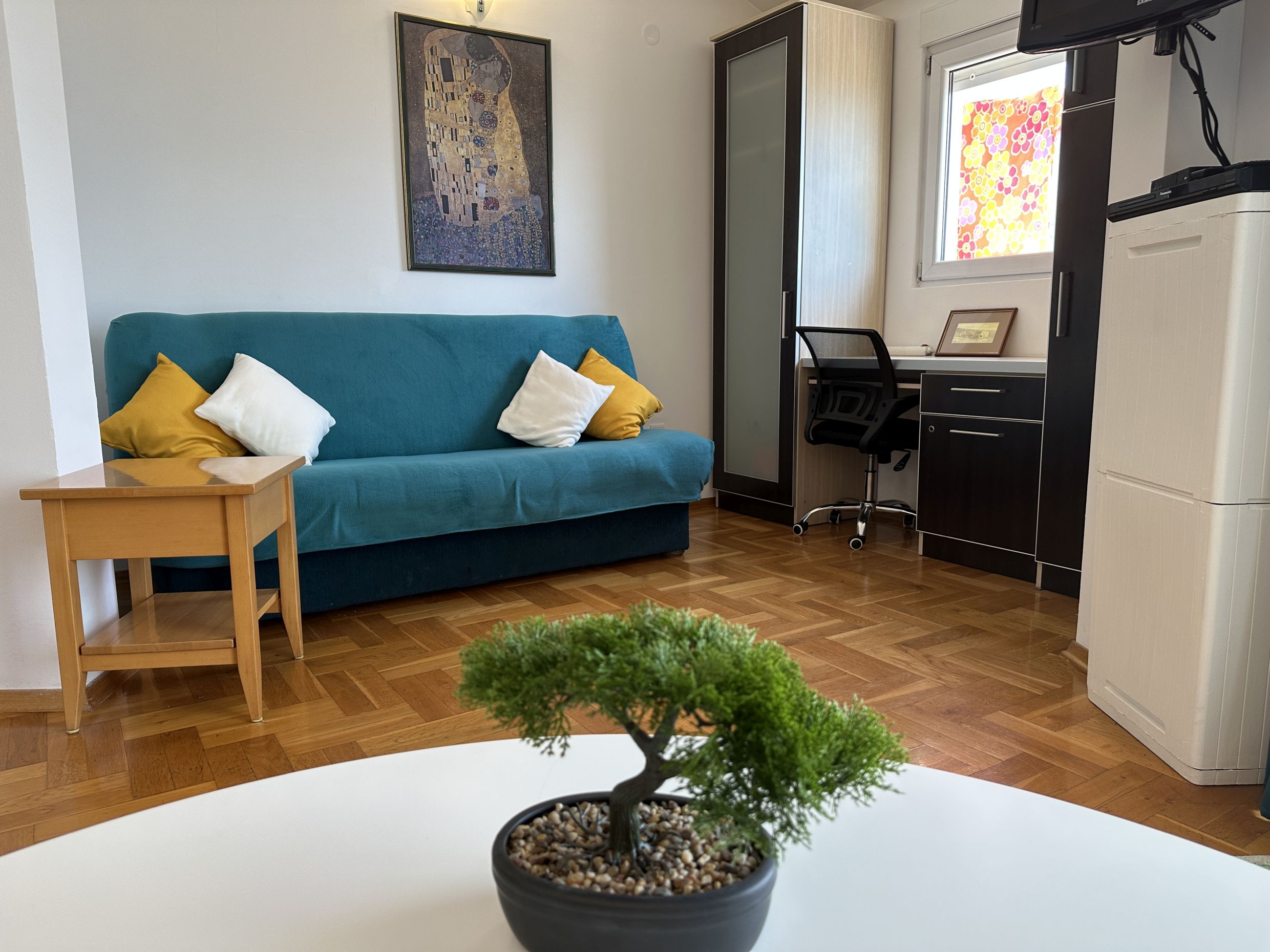 Living room in Bečići apartments, Montenegro: blue sofa, desk, parquet floor, and interior decor.
