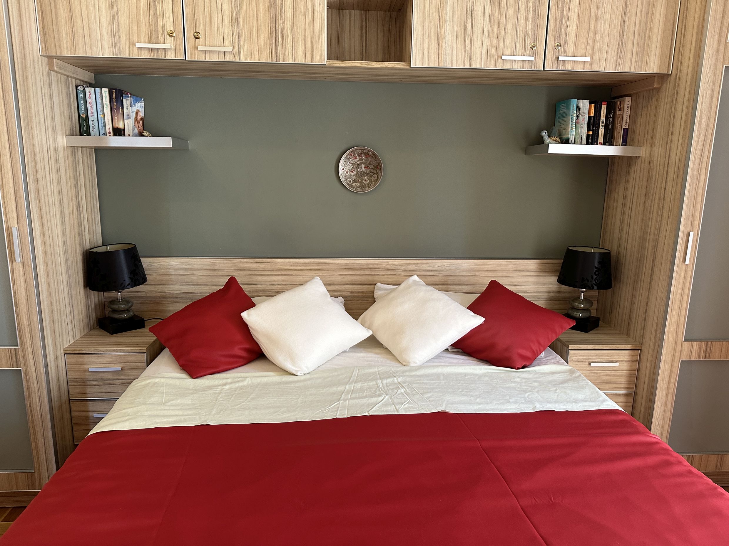 Bedroom in an apartment in Bečići, Montenegro: double bed, built-in wooden furniture, and bedside lamps.