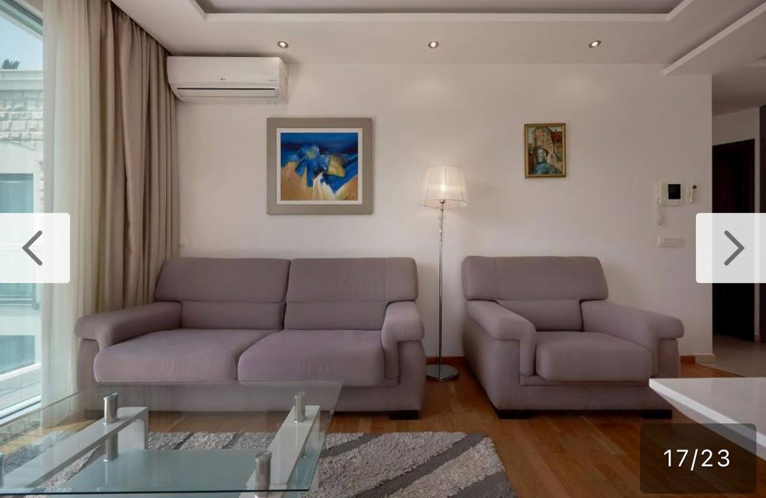 Modern living room in an apartment in Bečići, Montenegro: upholstered furniture, parquet flooring, air conditioning, and a panoramic window.