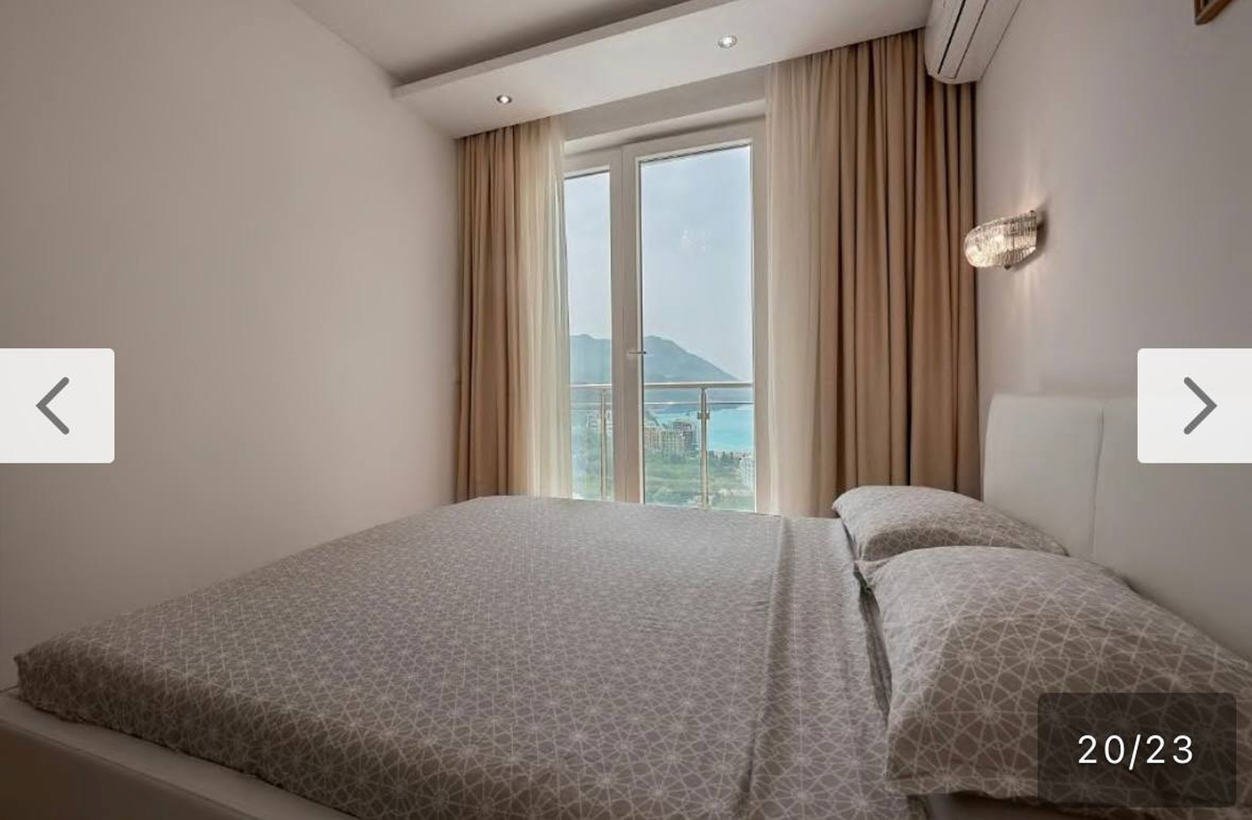 Bedroom in an apartment in Bečići, Montenegro: double bed, panoramic window with sea and mountain views, modern design.