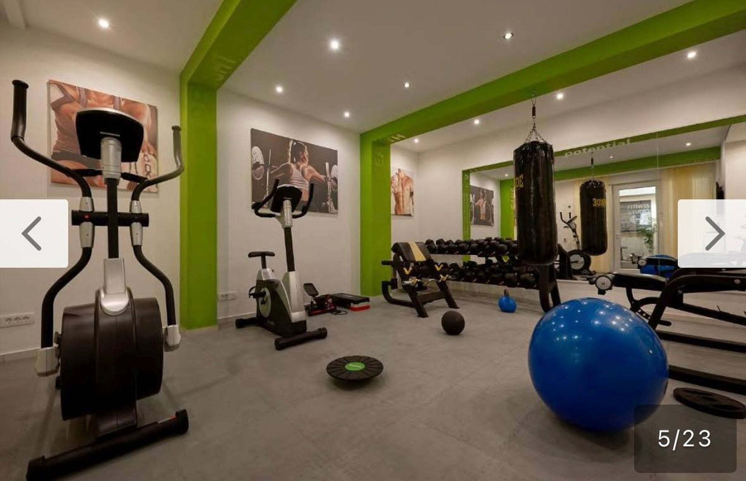 Modern gym with equipment in apartments, Bečići, Montenegro: cardio machines, dumbbells, and a punching bag.
