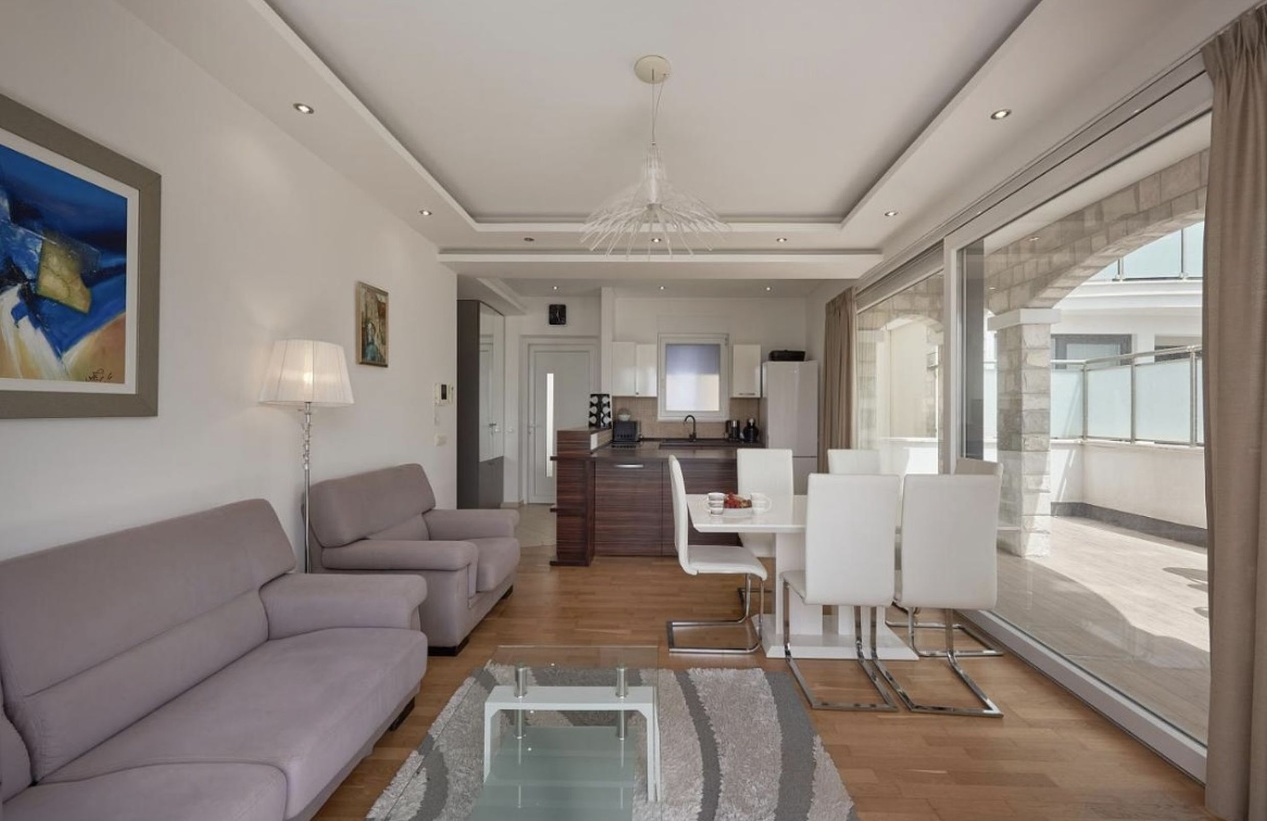 Modern living room with kitchen in an apartment in Bečići, Montenegro: soft furnishings, dining area, and access to the terrace.