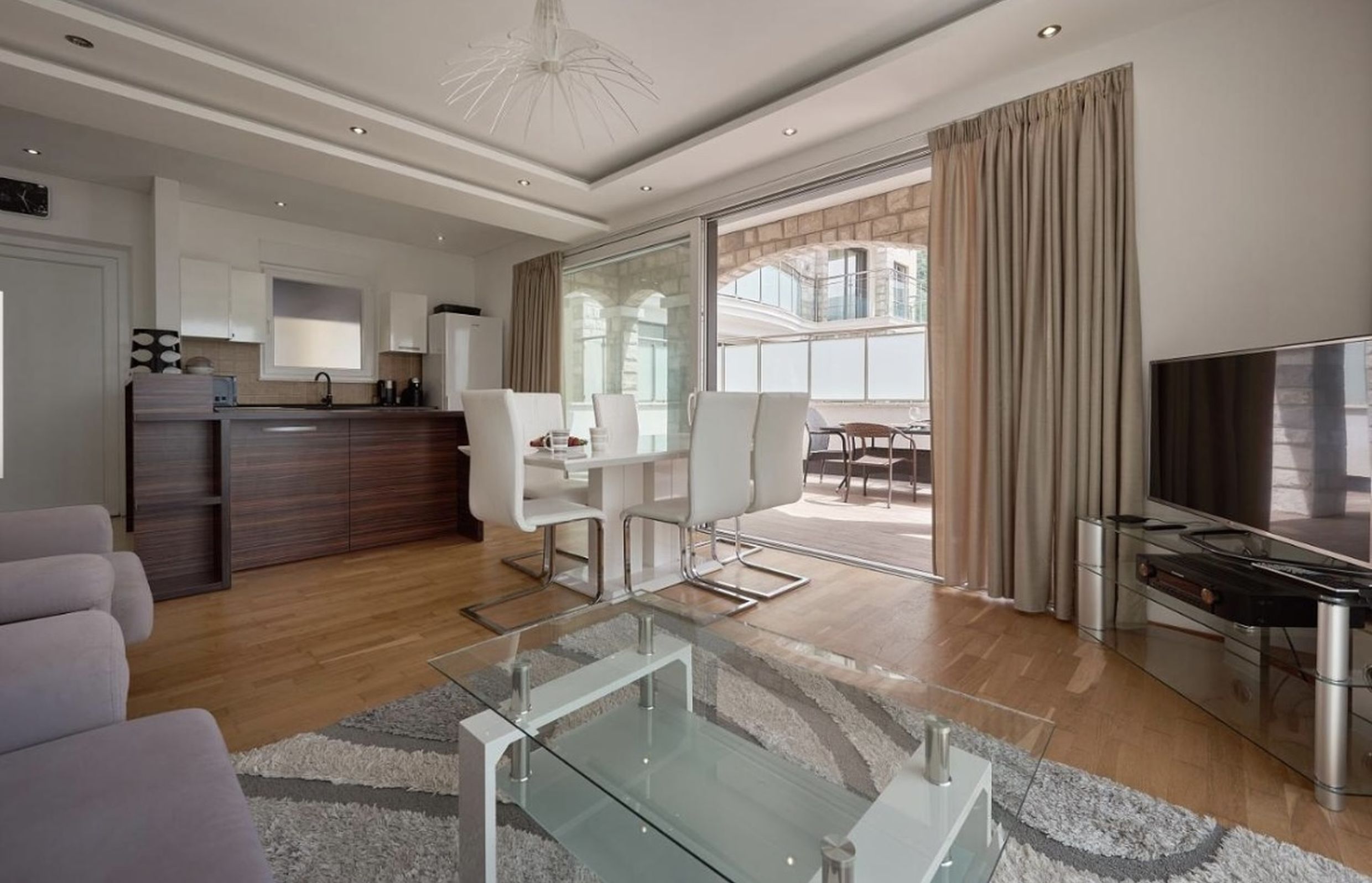 Modern living room with kitchen and terrace access in an apartment, Bečići, Montenegro: bright interior, furniture, and view.