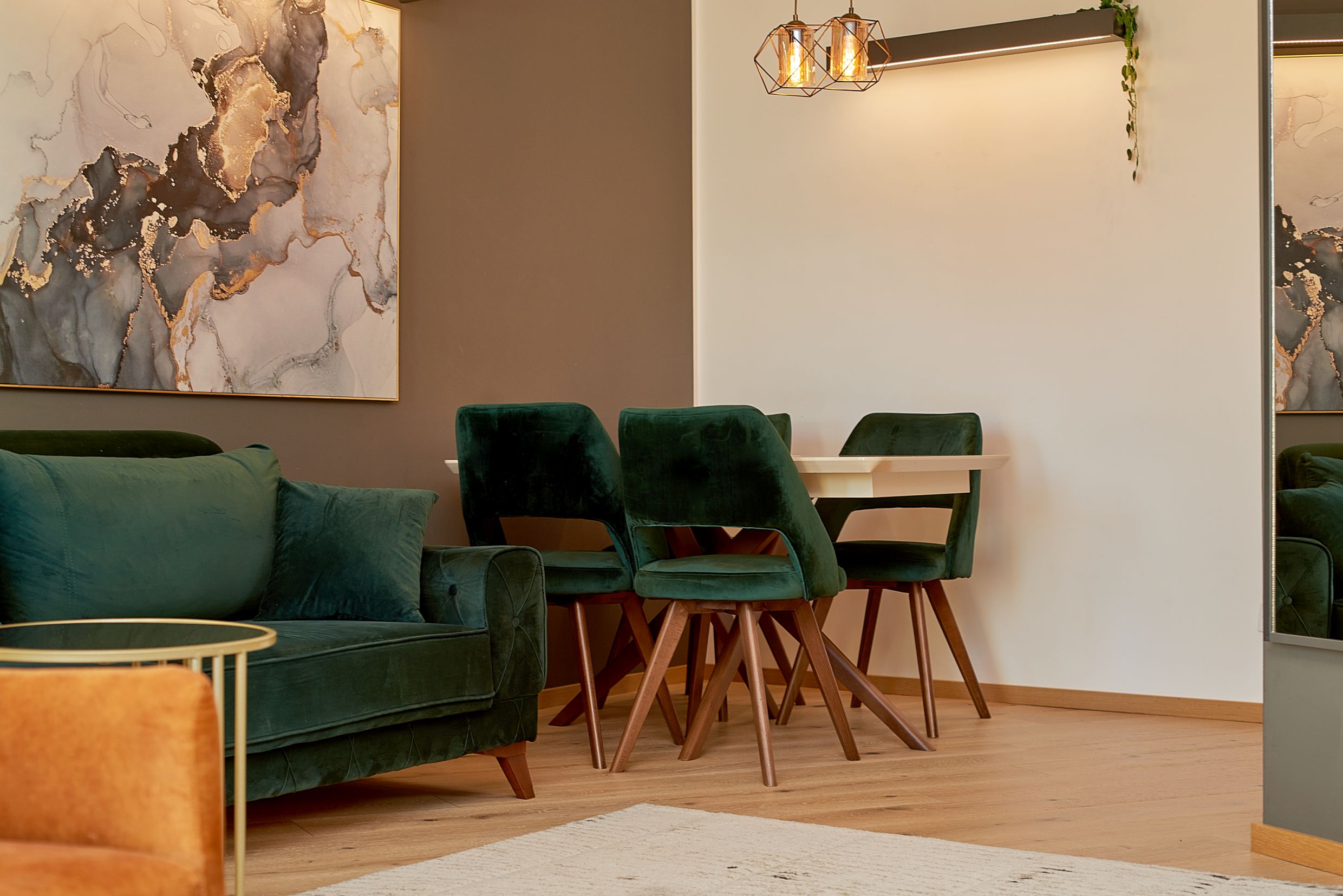 Modern living room with emerald velvet armchairs and a dining area in an apartment in Bečići, Montenegro.