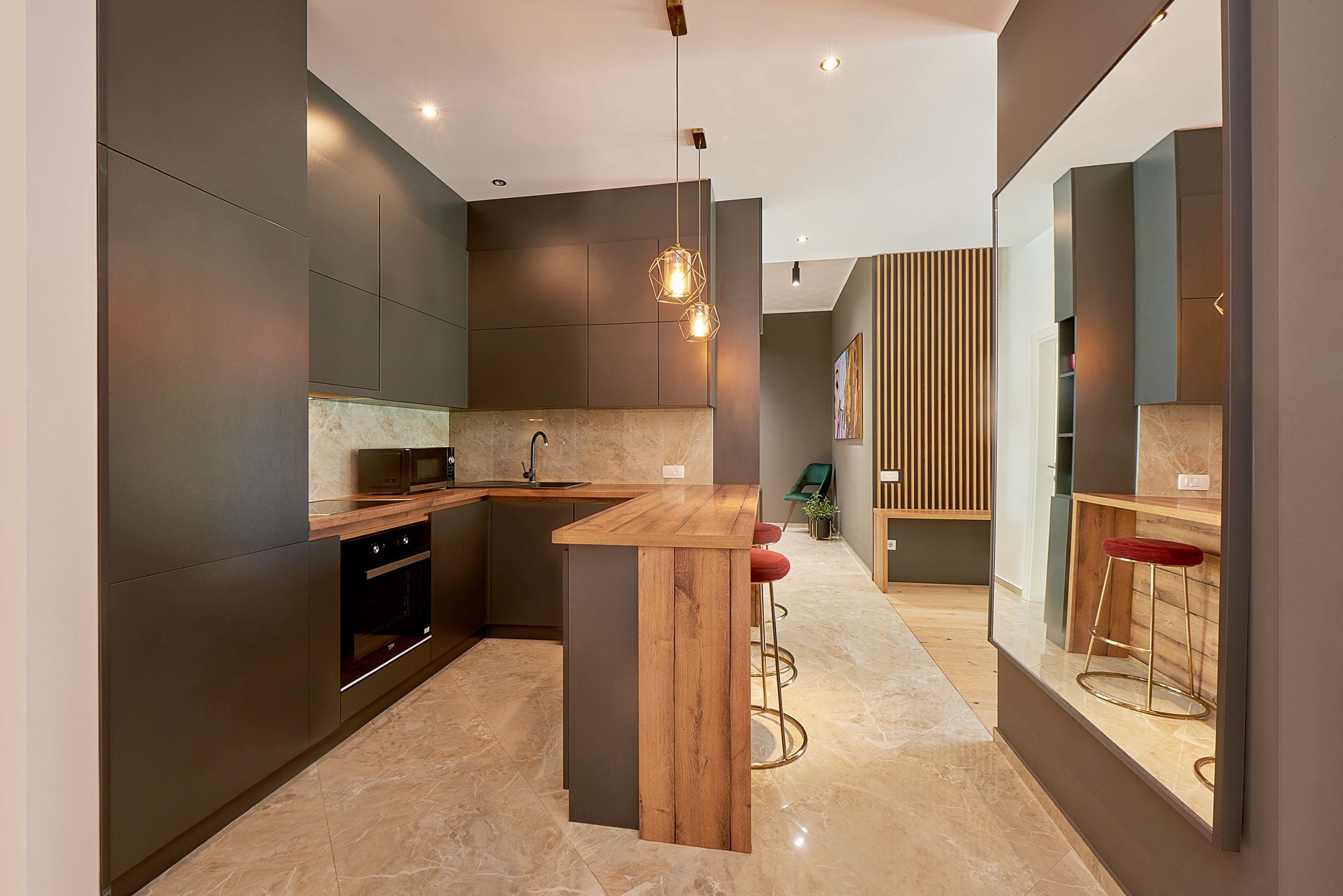 Modern kitchen in Bečići apartments, Montenegro: dark facades, bar counter, marble floor, and stylish decor.