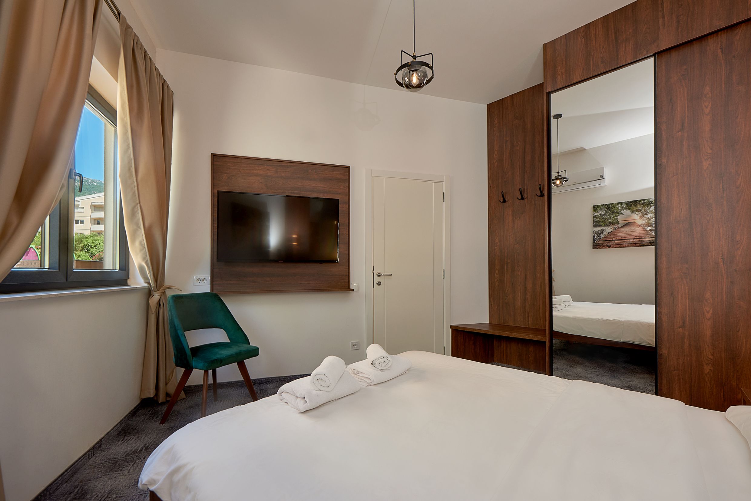 Modern bedroom in Bečići apartments, Montenegro: double bed, mirrored wardrobe, and view from the window.