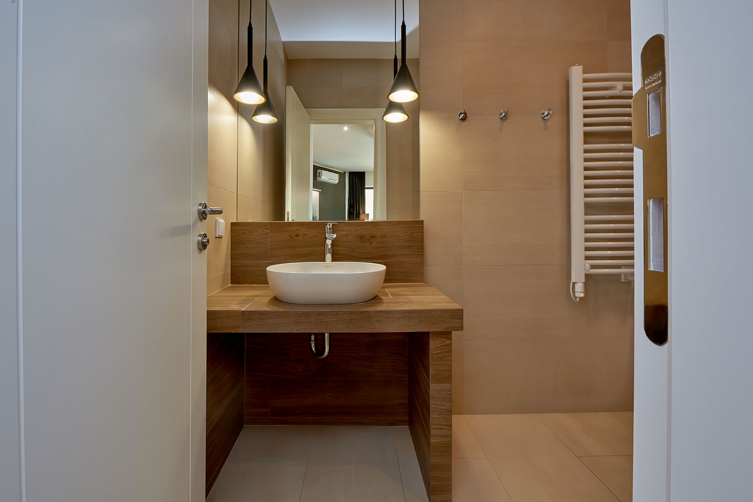Modern bathroom in an apartment in Bečići, Montenegro: countertop sink, wood-style finish, and towel warmer.