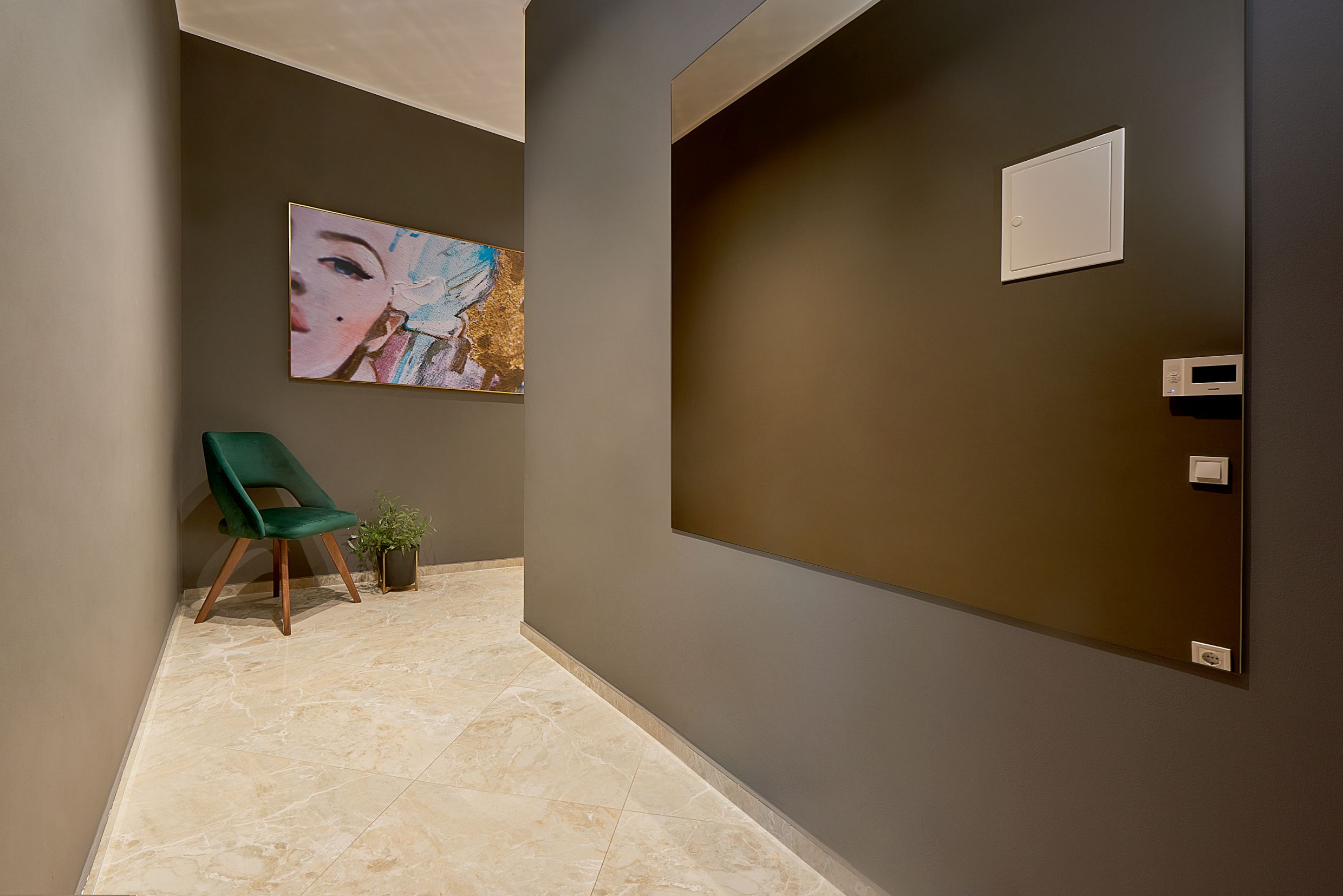 Modern hallway interior in an apartment, Bečići, Montenegro: gray finishes, a green armchair, and a wall mirror.