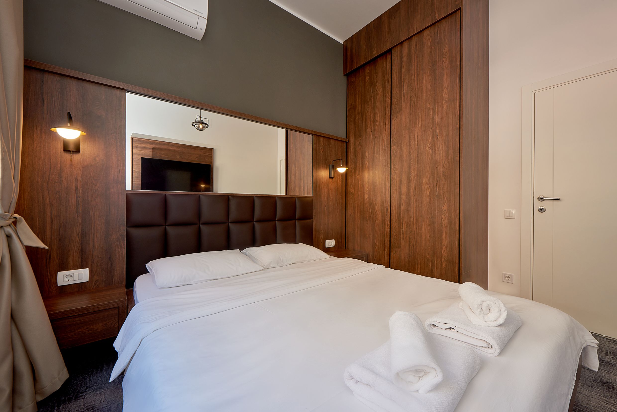 Modern bedroom with a double bed and wooden wardrobe in an apartment in Bečići, Montenegro.