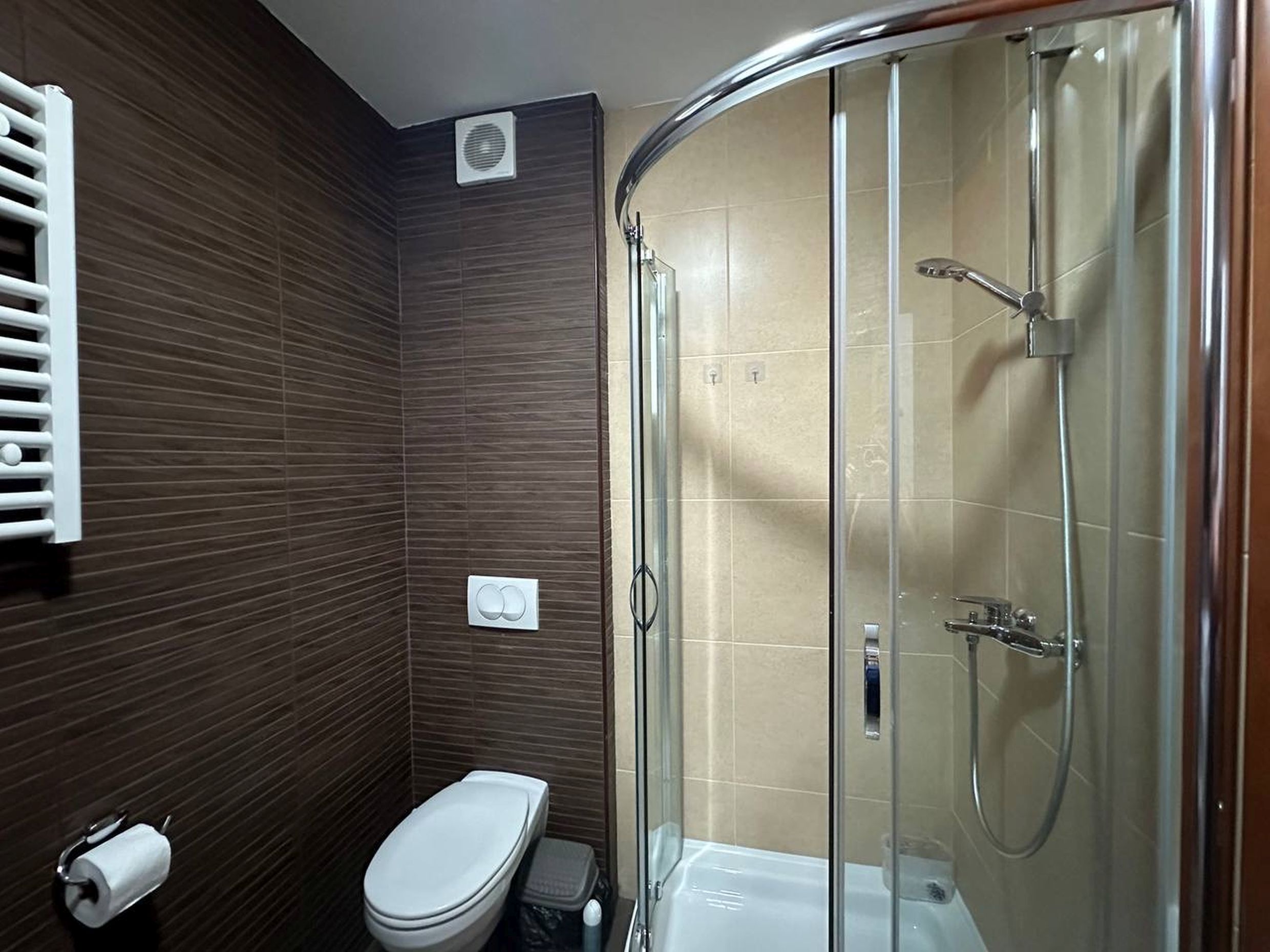 Modern bathroom in an apartment in Becici, Montenegro: walk-in shower, brown tiles, and sanitary ware.