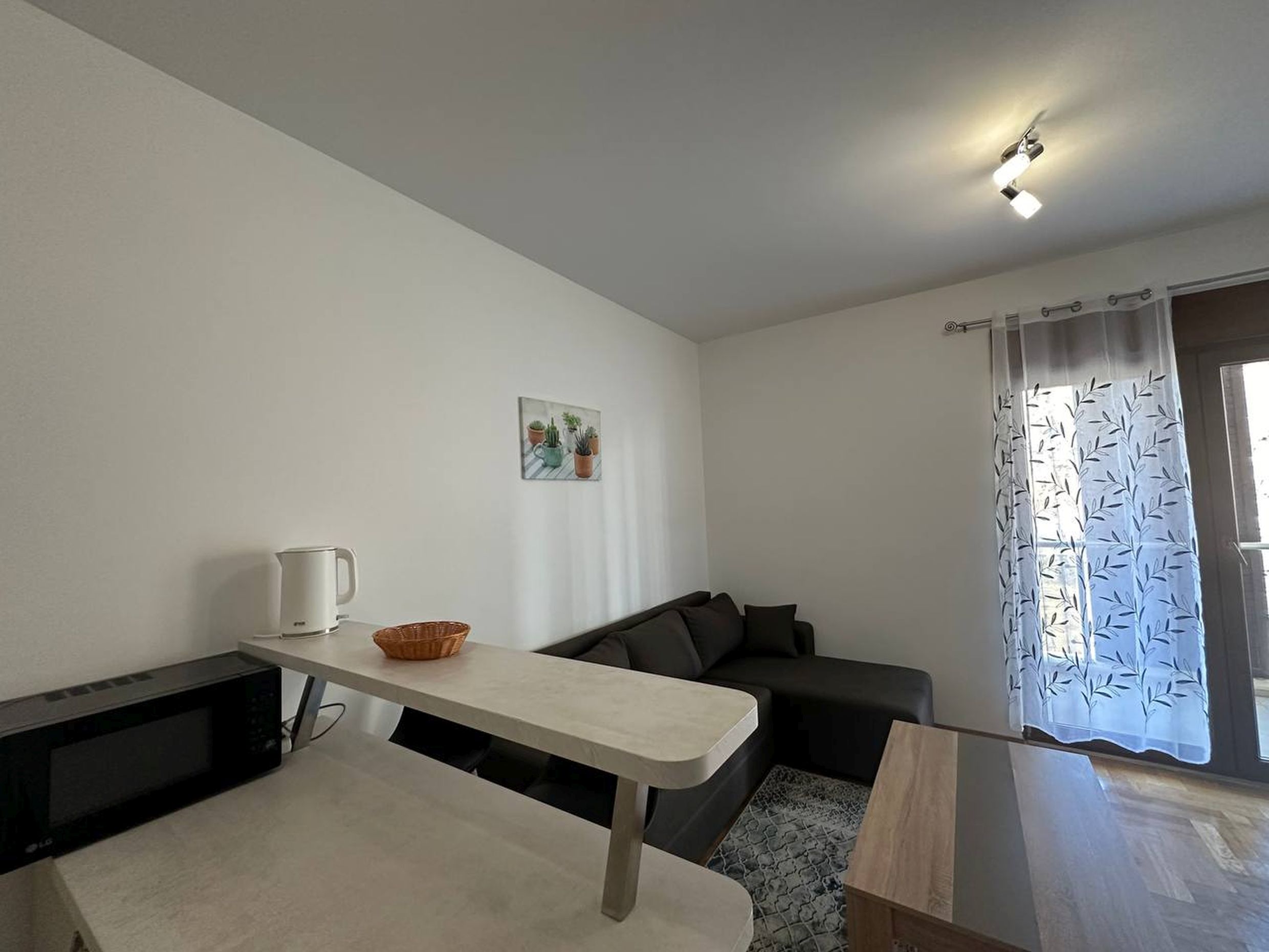 Living room with a sofa and a breakfast bar in an apartment in Bečići, Montenegro. Modern interior with access to a balcony.