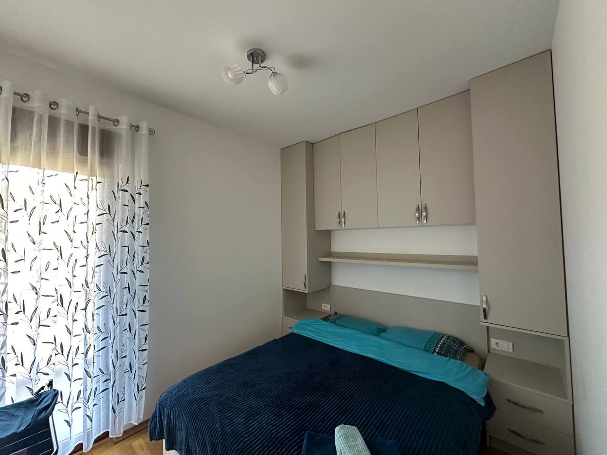 Cozy bedroom with a double bed and a built-in wardrobe in an apartment in Becici, Montenegro.
