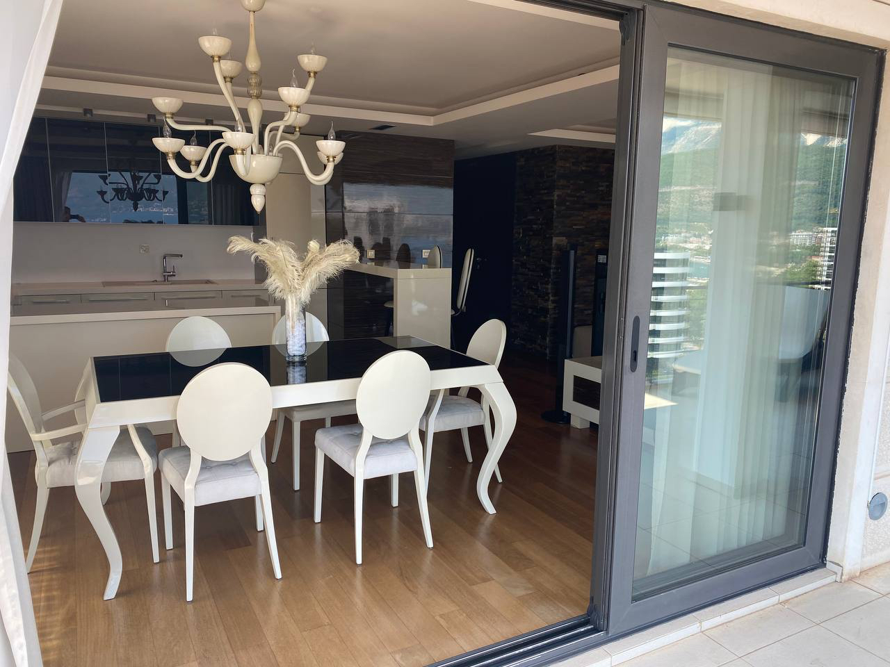 Modern living room with dining area in an apartment in Budva, Montenegro, with panoramic views and designer furniture.