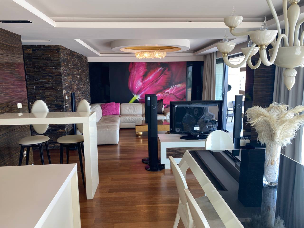 Modern living room in an apartment in Budva, Montenegro: leather sofa, stone finishes, dining area, and TV area.