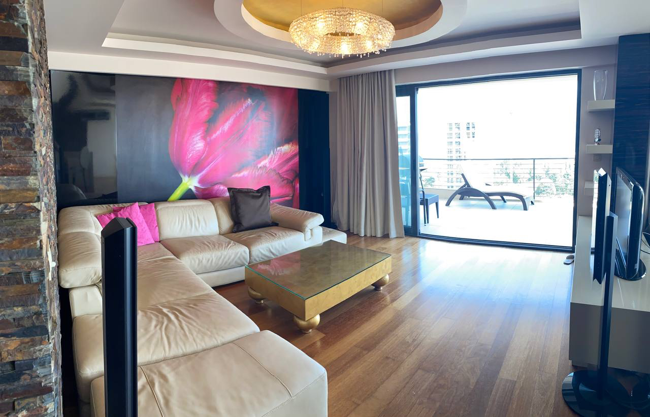 Living room in an apartment in Budva, Montenegro: leather sofa, designer wall finishes, terrace with a view, and parquet flooring.