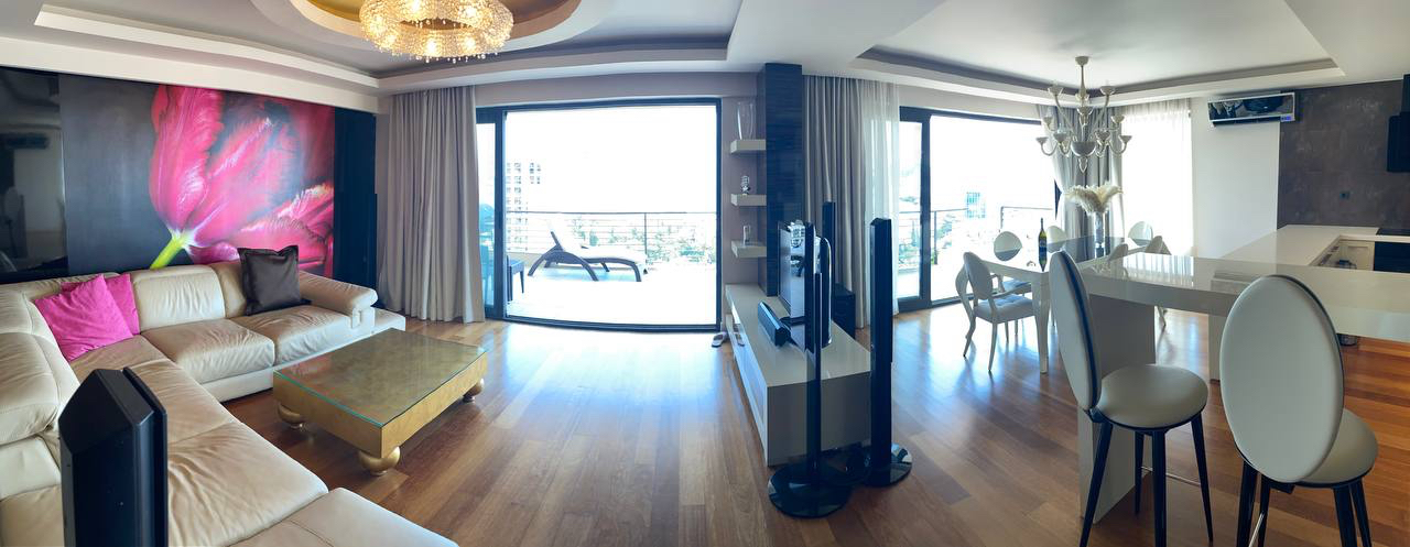 Spacious living room with a leather sofa and terrace in a luxury apartment, Budva, Montenegro. Modern interior with a view.