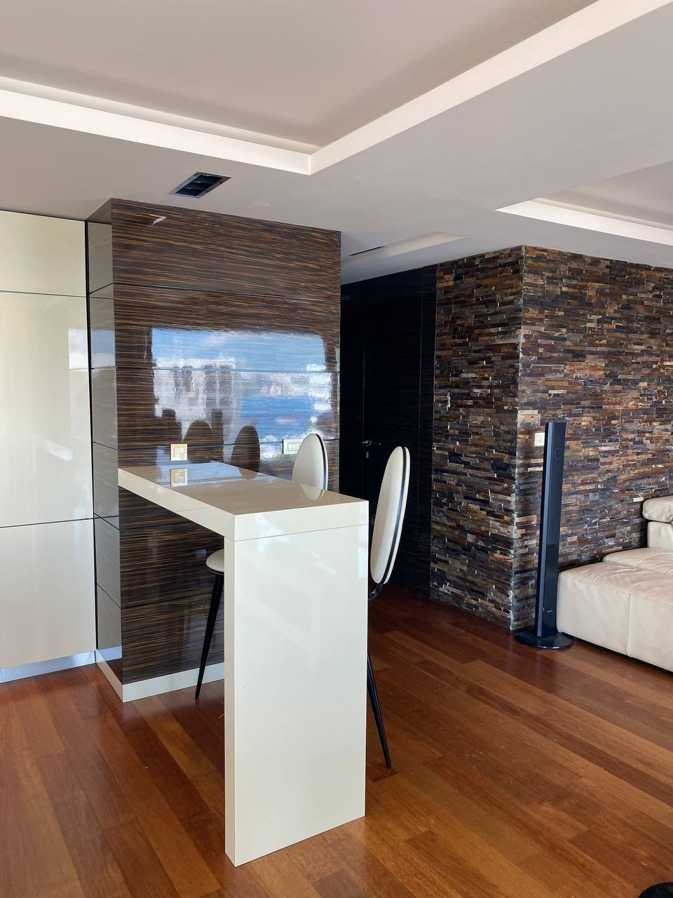 Modern living room in an apartment in Budva, Montenegro: bar counter, stone and glossy panel finishes, parquet flooring.