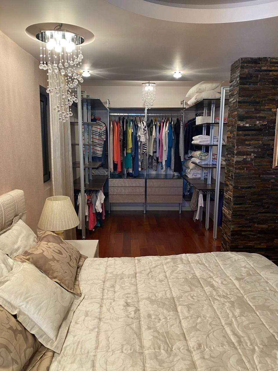 Bedroom with an open walk-in closet, bed, and stone finishes in an apartment in Budva, Montenegro.
