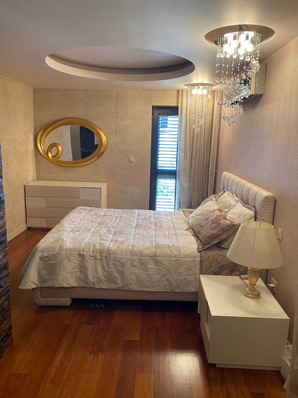 Cozy bedroom with a double bed and designer lighting in an apartment for sale, Budva, Montenegro.
