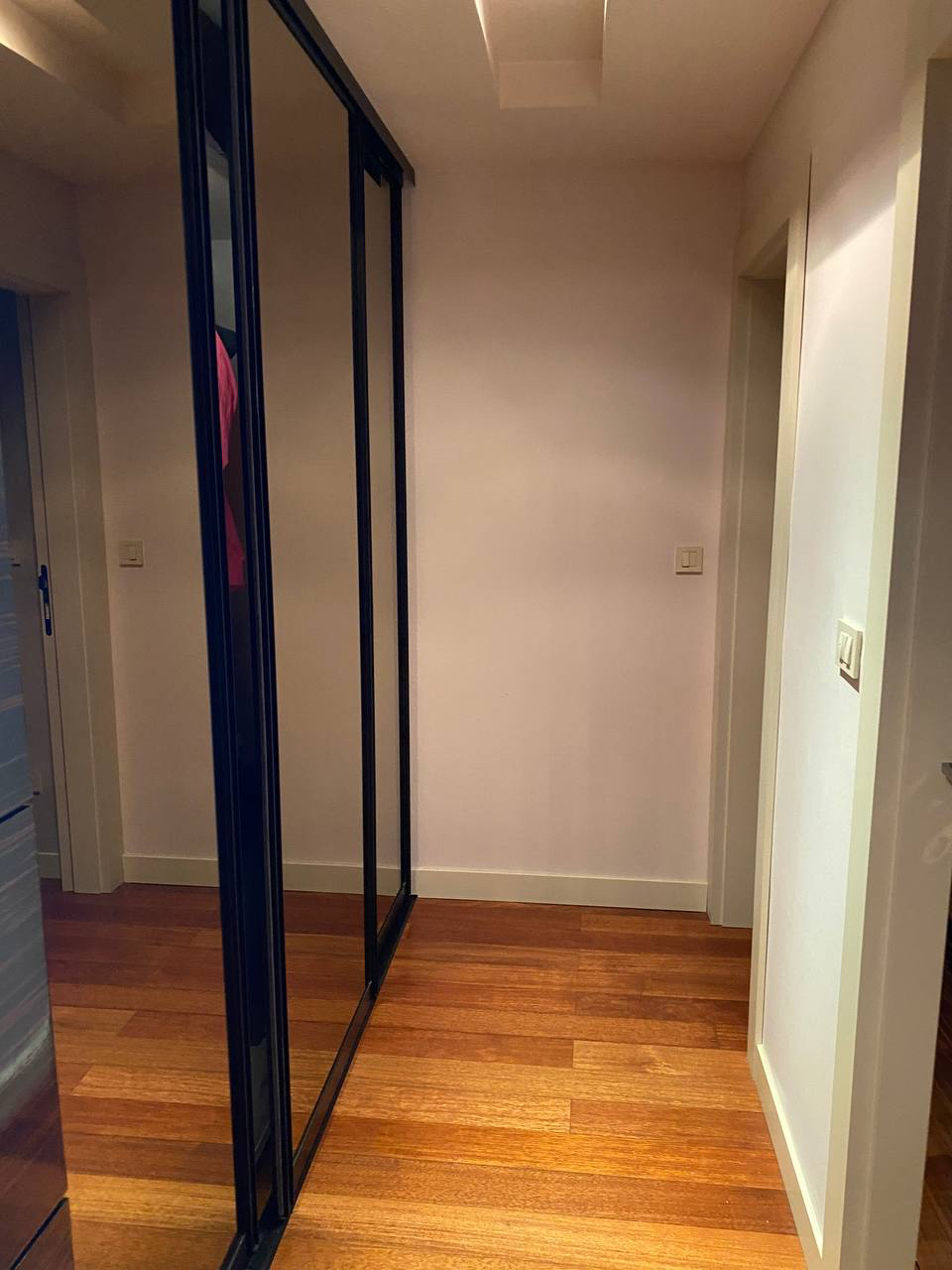 Hallway with a mirrored sliding wardrobe and parquet flooring in a modern apartment, Budva, Montenegro.