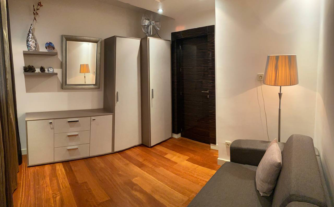 Living room interior in an apartment in Budva, Montenegro: gray sofa, light-colored cabinet, dresser, and parquet flooring.