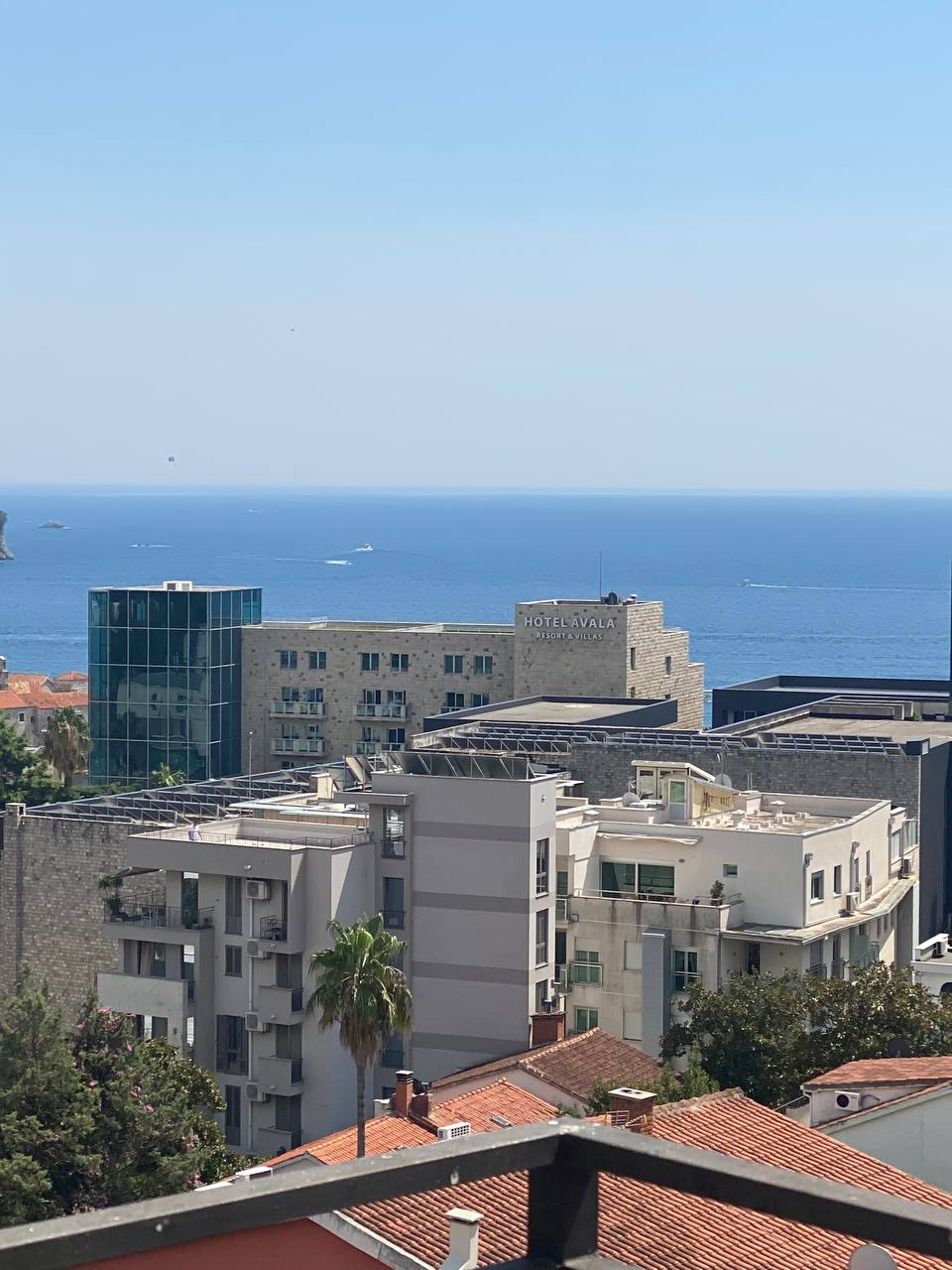View from the apartment balcony in Budva, Montenegro: city panorama, the Avala Hotel, and the Adriatic Sea on the horizon.
