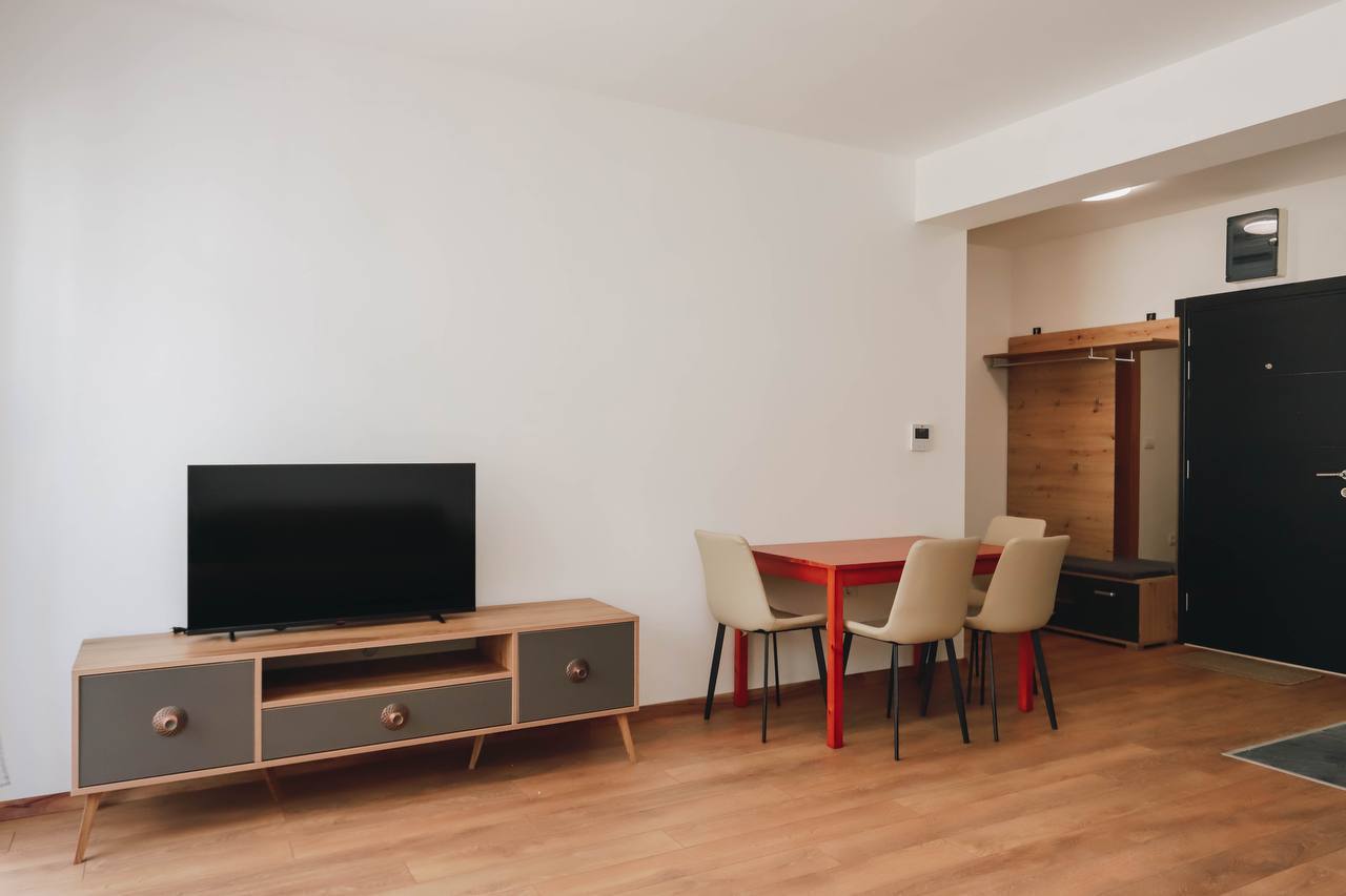Living room in an apartment in Budva, Montenegro: a modern TV stand, dining table with chairs, and an entryway with finishes.