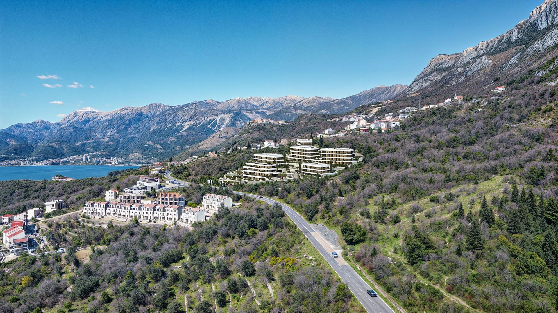 Aerial view of a residential complex in Reževići, Montenegro: modern buildings among the mountains and a panoramic sea view.