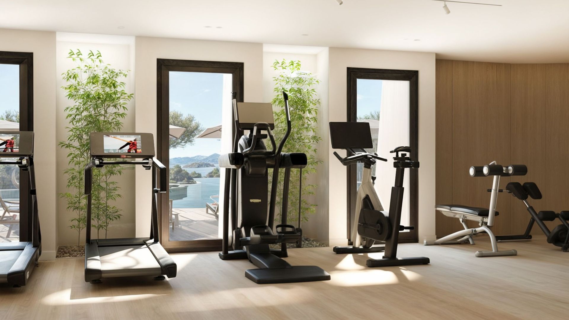 Modern gym in the Reževići residential complex, Montenegro: treadmill, elliptical trainer, and sea view through panoramic windows.