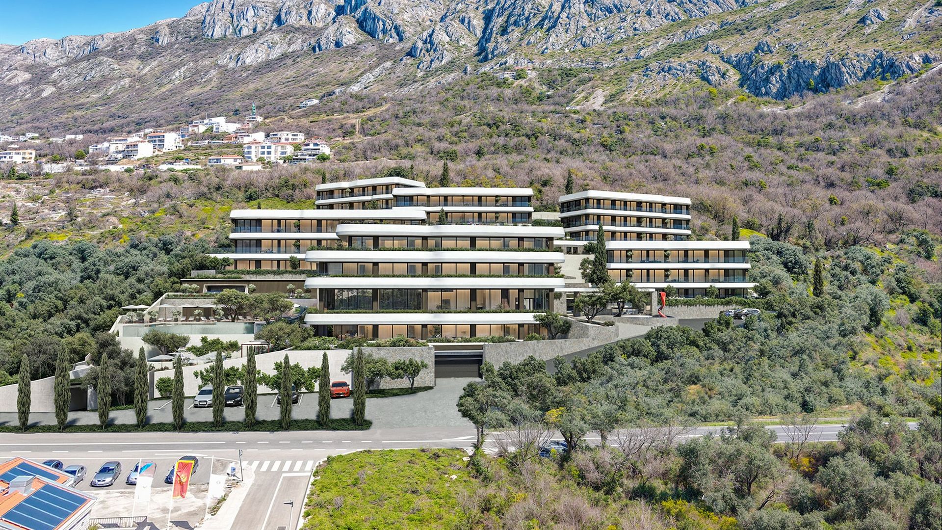 Modern residential complex in Reževići, Montenegro: panoramic view of cascading buildings with terraces at the foot of the mountains.