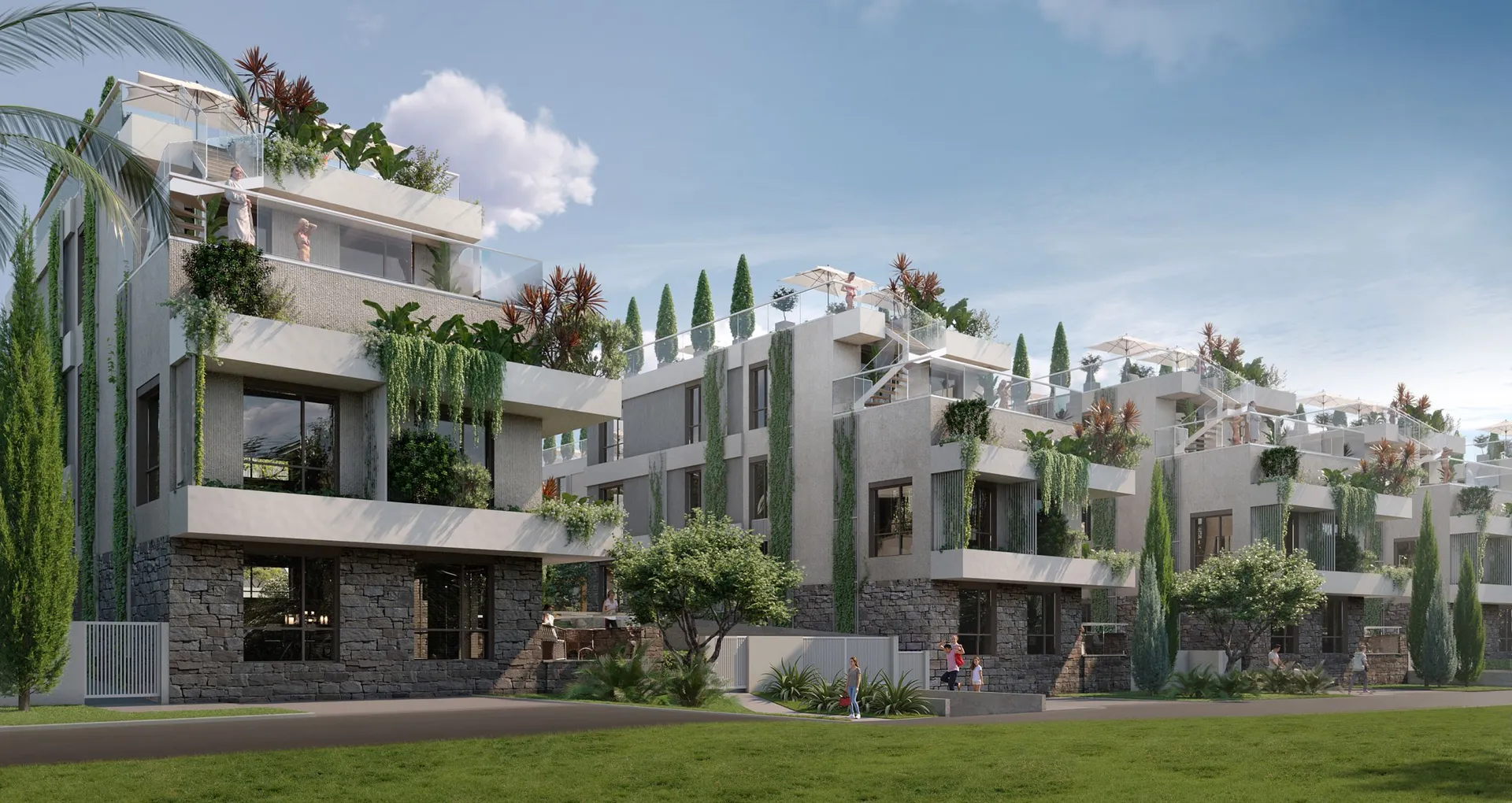 Modern residential complex with terraces, lush greenery, and stone facade under a clear sky.