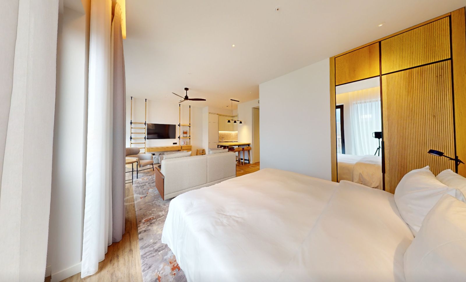 Modern bedroom with living area in an apartment in Tivat, Montenegro: bright interior, double bed, and kitchen.