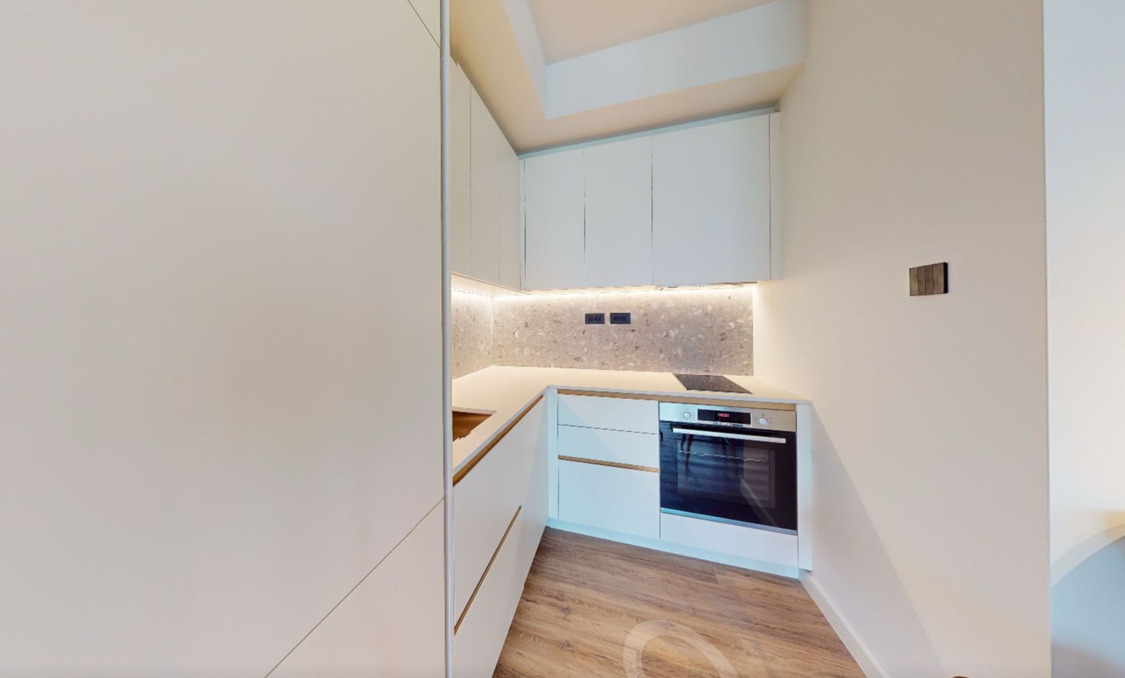 Modern white kitchen with a stone backsplash and built-in appliances in an apartment, Tivat, Montenegro.