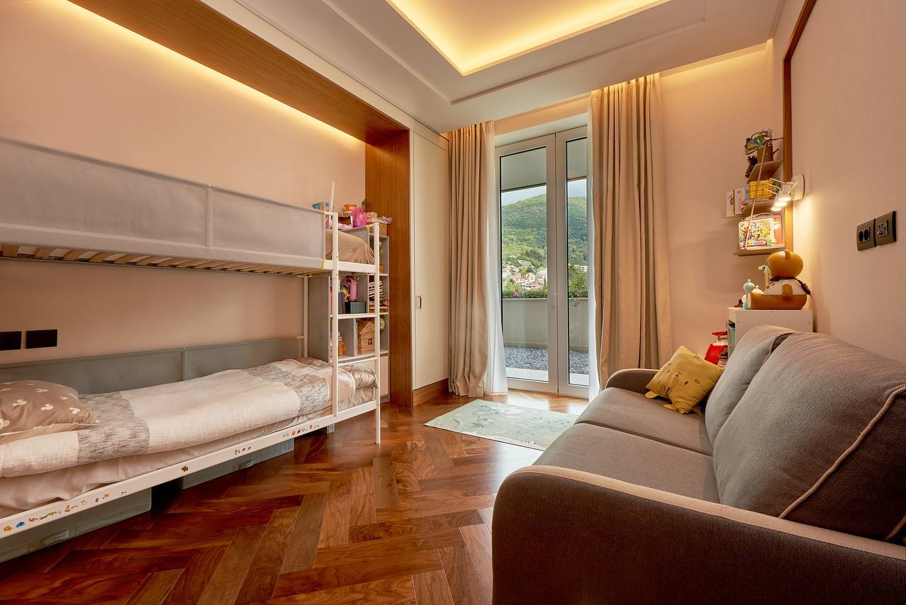 Children's bedroom with a bunk bed and sofa in an apartment, Tivat, Montenegro. Mountain view from a panoramic window.