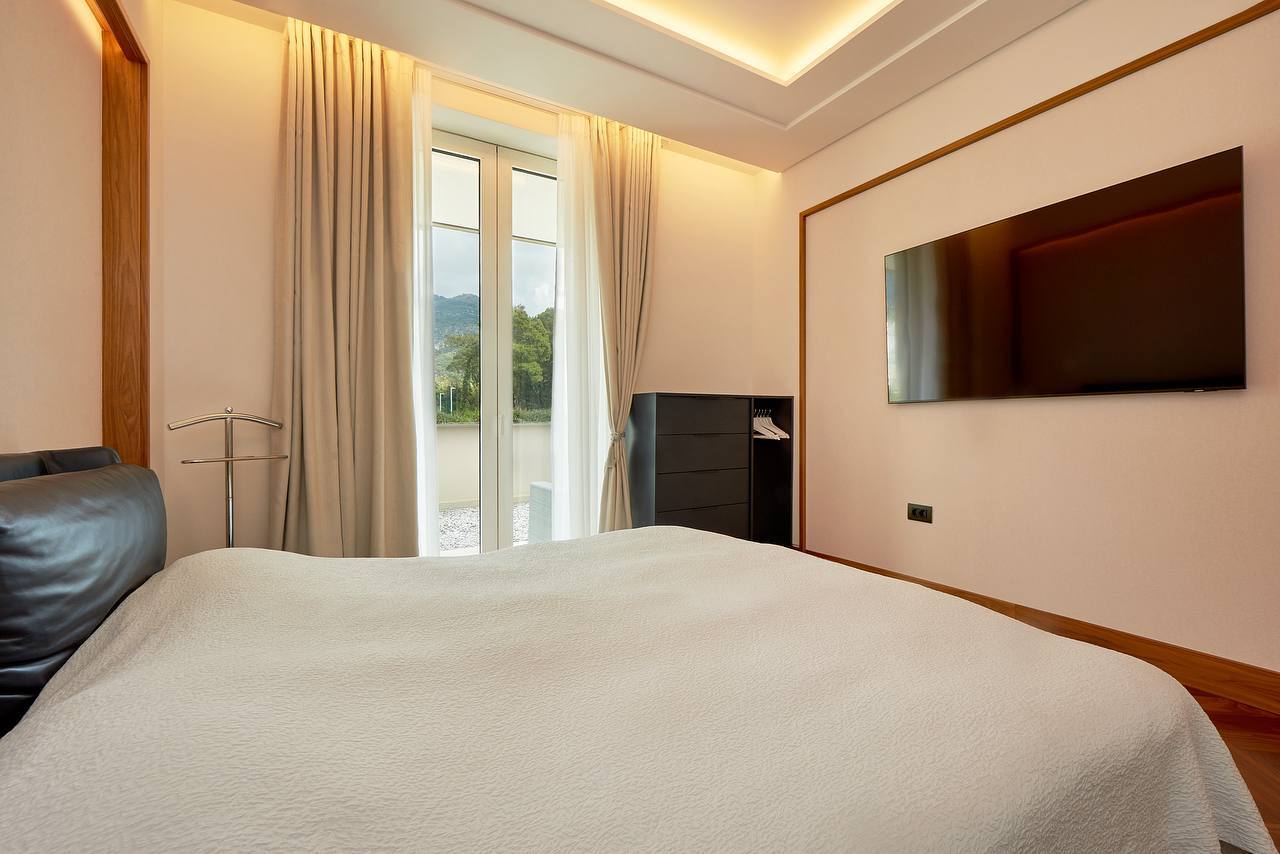 Modern bedroom in an apartment in Porto Montenegro, Tivat, Montenegro: double bed, TV, and mountain view.