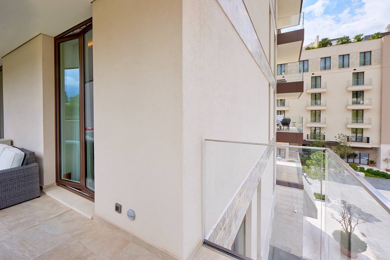 Balcony of a modern apartment in Porto Montenegro, Tivat, Montenegro, with panoramic glazing and a view of the complex.
