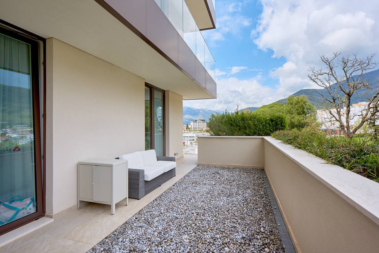 Spacious terrace with furniture in a luxury apartment in Porto Montenegro, Tivat, Montenegro, with mountain and city views.