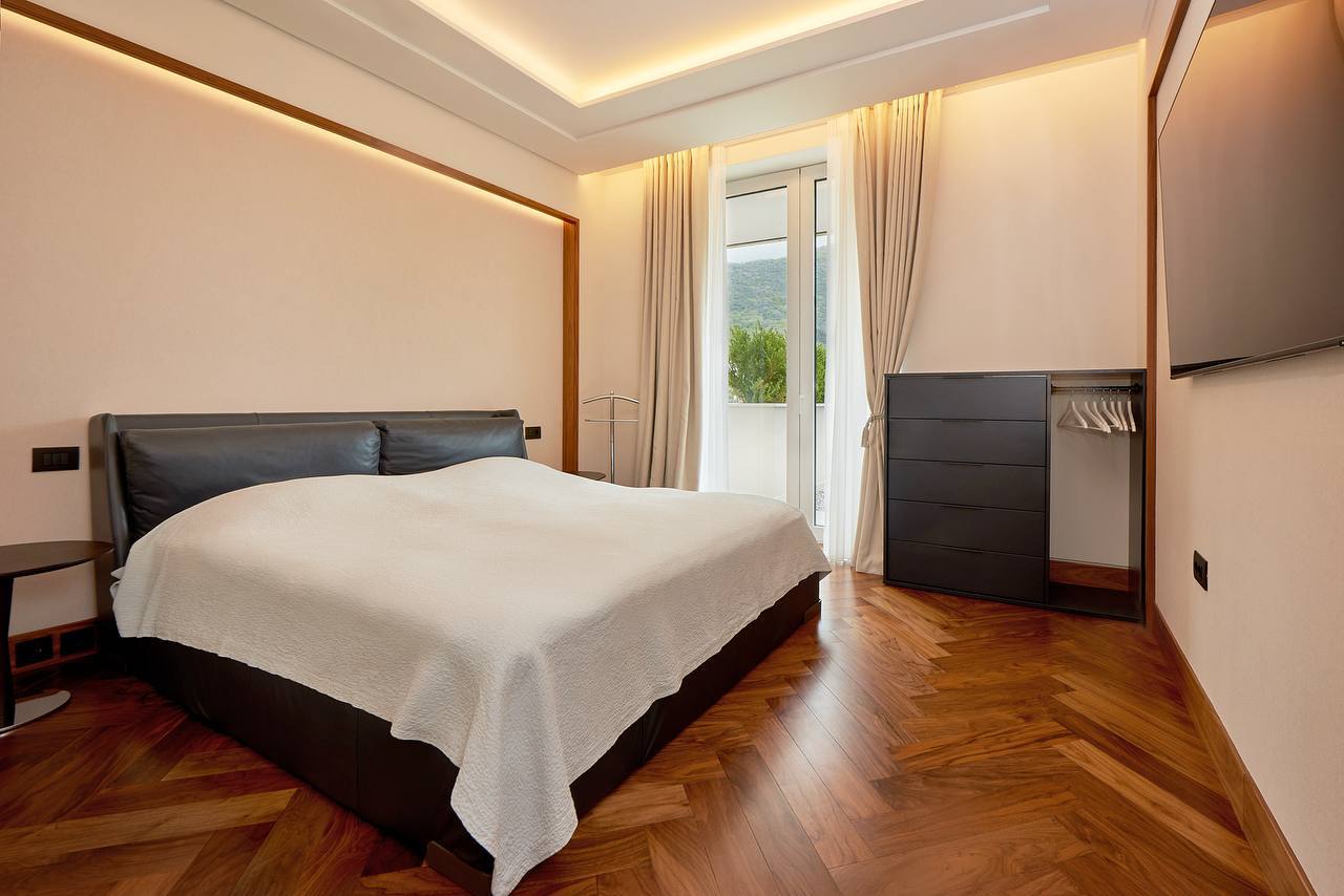 Modern bedroom with a double bed and parquet flooring in an apartment in Porto Montenegro, Tivat, Montenegro.