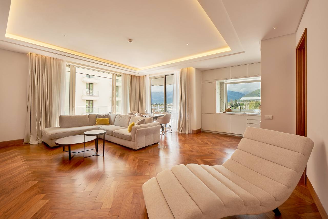 Modern living room in Porto Montenegro, Tivat, Montenegro: light furniture, herringbone parquet, and mountain views.