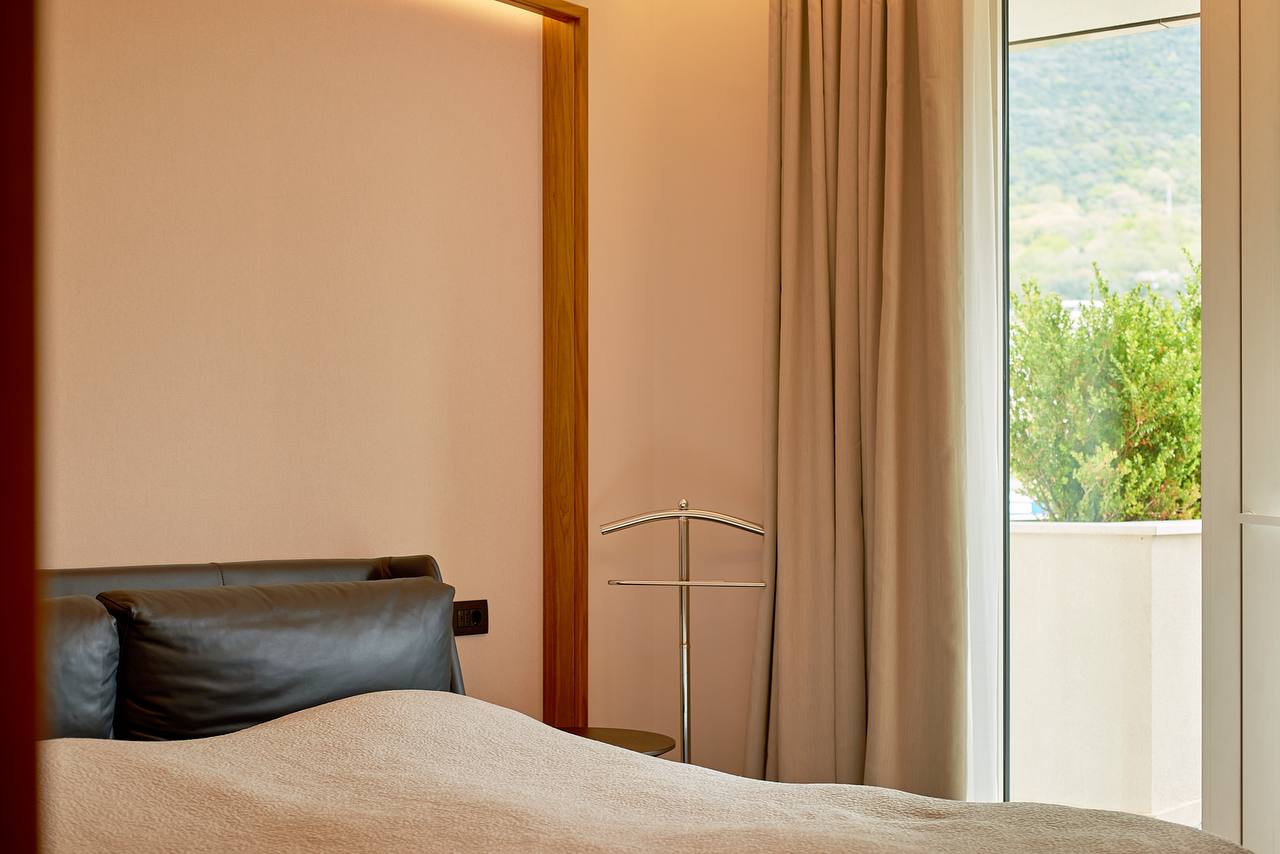 Modern bedroom in an apartment in Porto Montenegro, Tivat, Montenegro: leather bed, view of greenery and terrace.