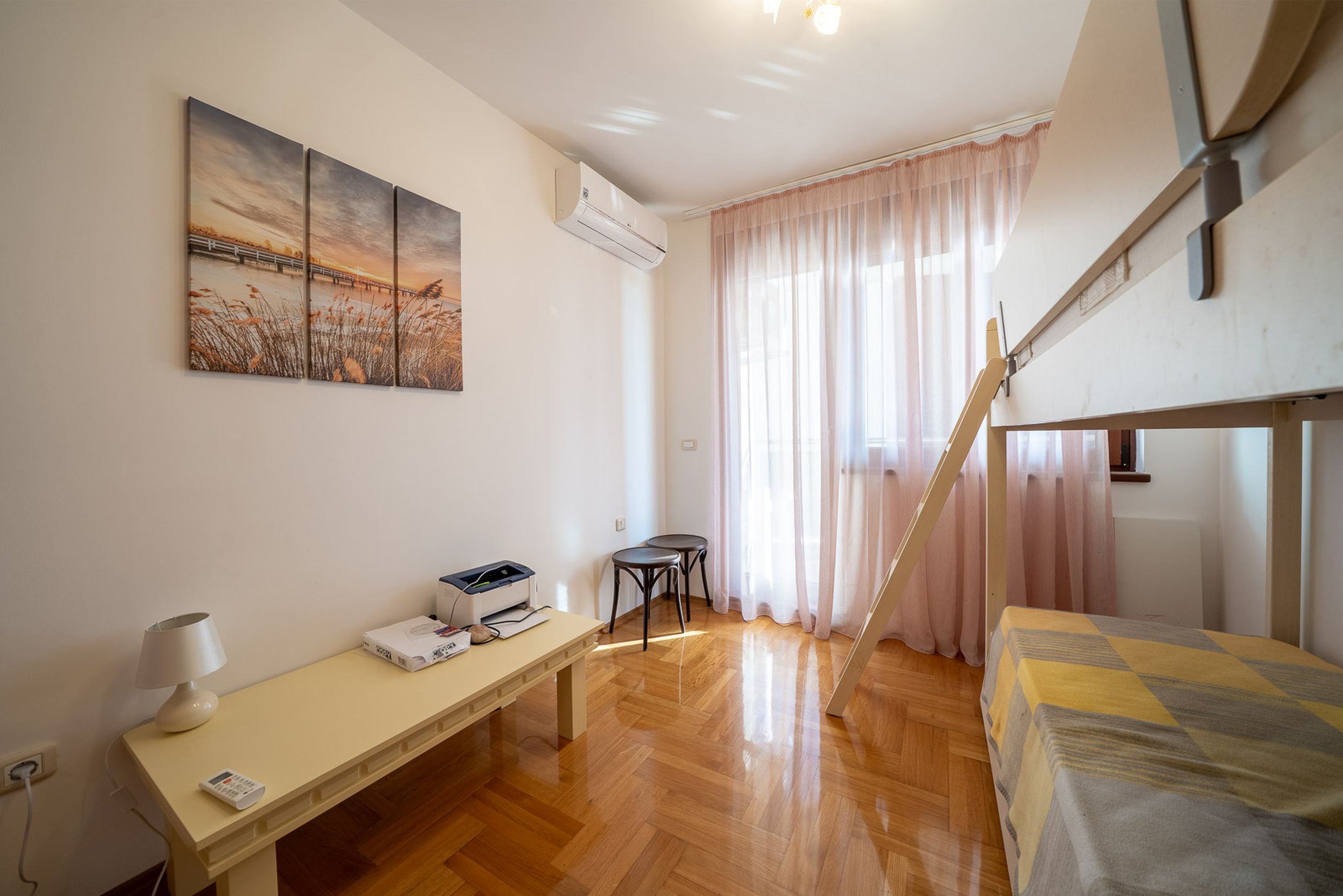 Bedroom with a bunk bed and parquet flooring in an apartment in Bečići, Montenegro: bright interior with air conditioning.