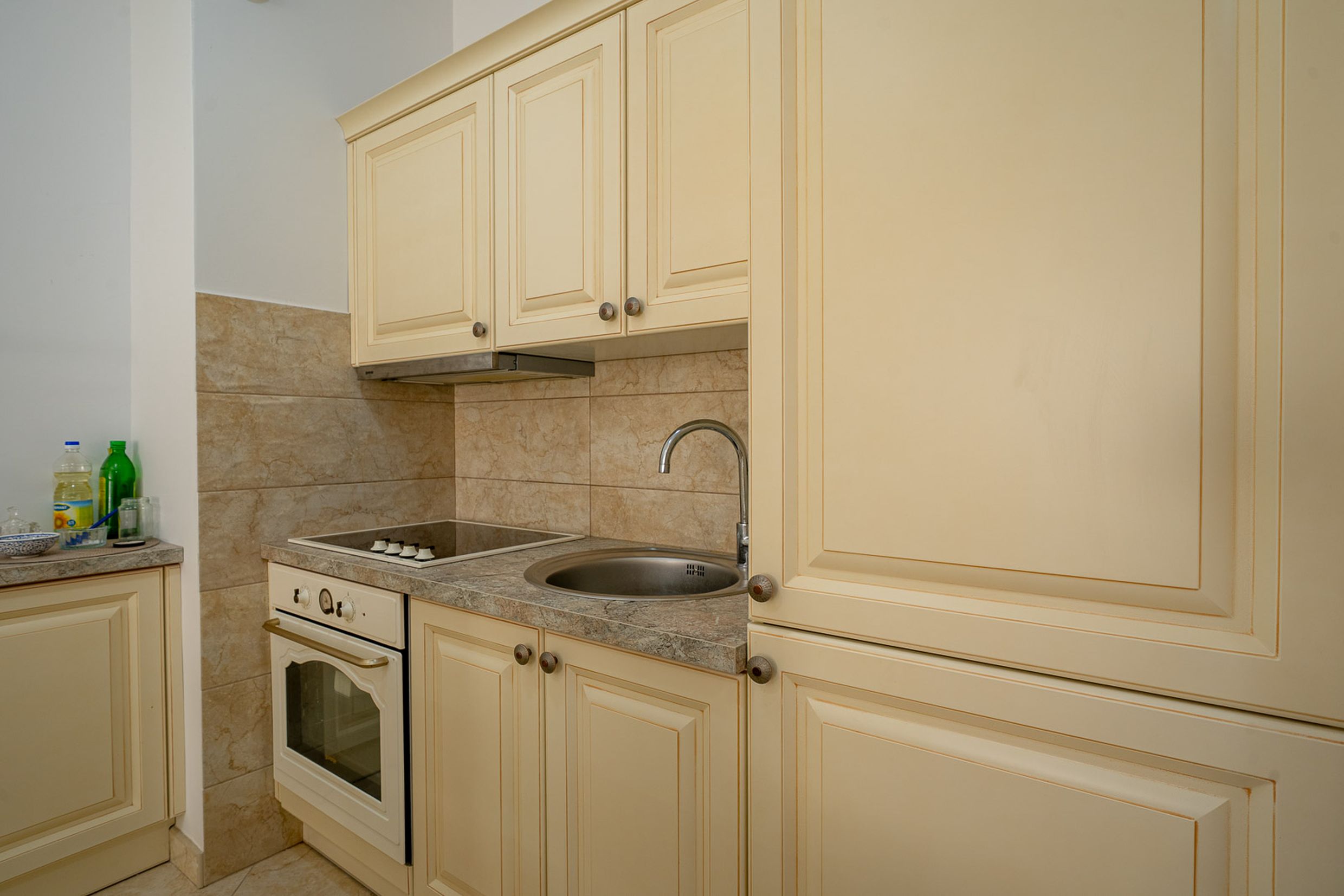 Bright kitchen in an apartment in Bečići, Montenegro: built-in appliances, beige cabinets, and a stone countertop.
