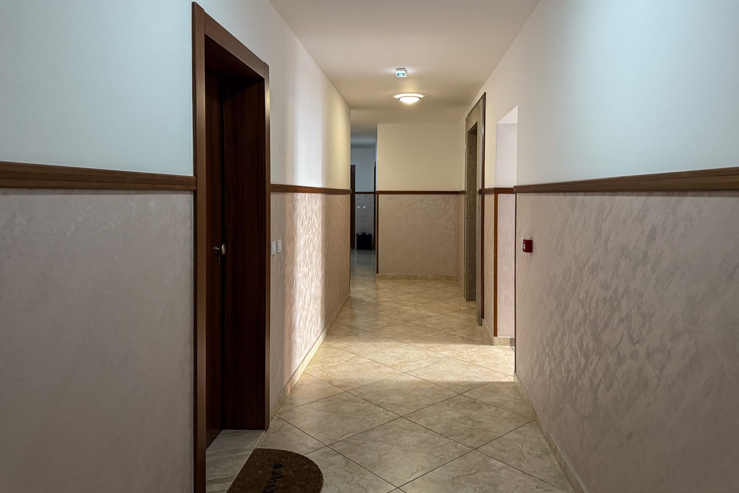 Bright hallway in an apartment in Bečići, Montenegro: tiled floor, walls finished with decorative plaster and wood.